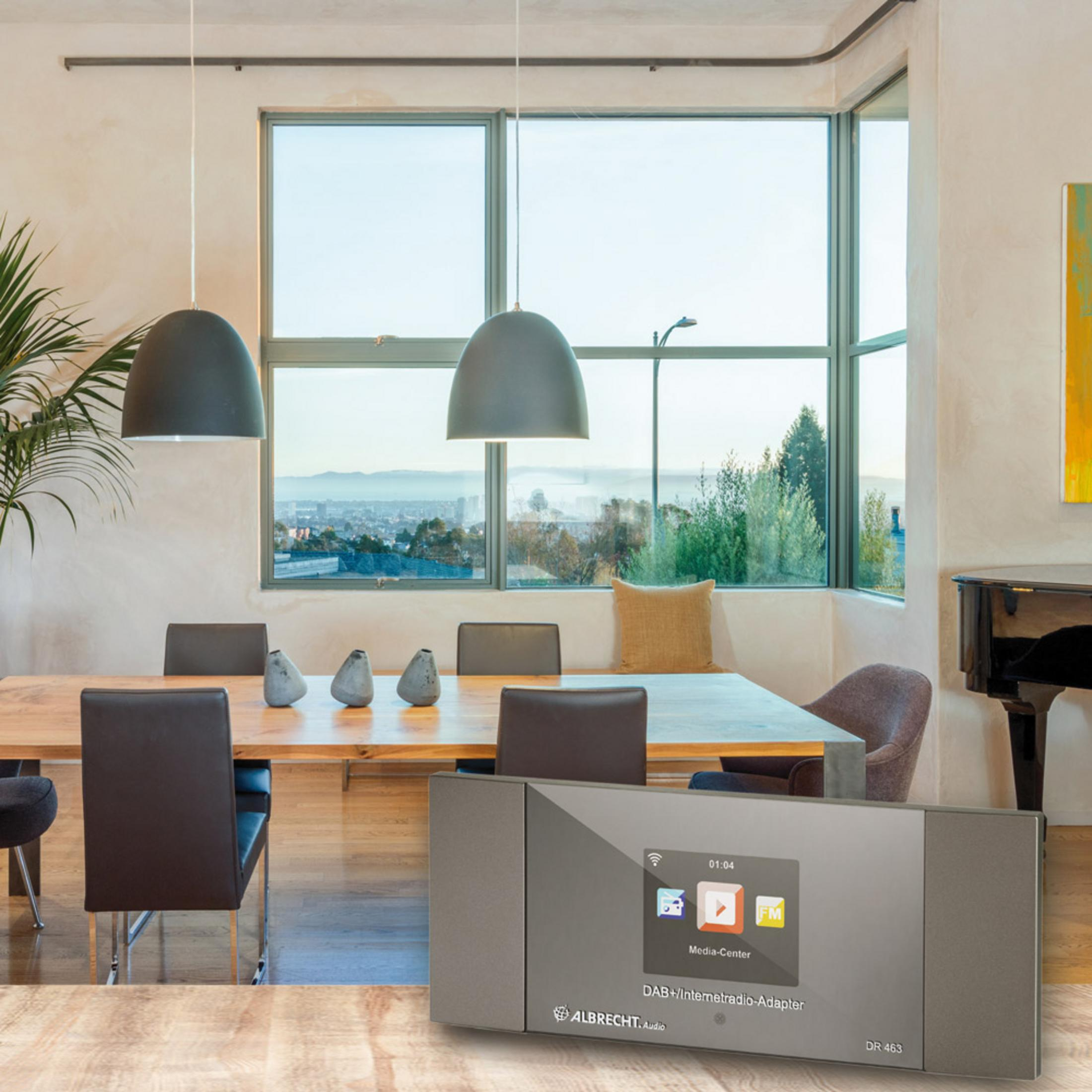 Jadalnia z nowoczesnym radiem, stołem, krzesłami i dużymi oknami z widokiem na miasto.