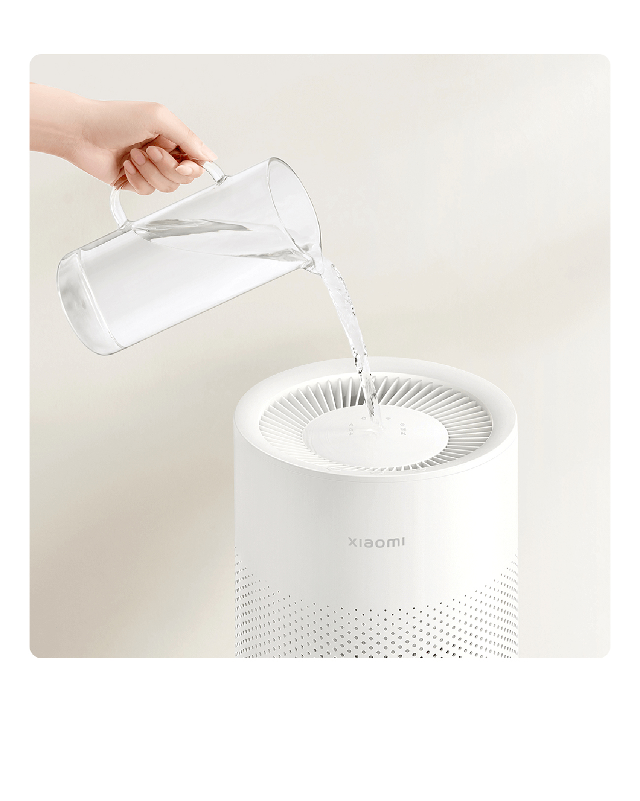 Una mano vertiendo agua en un purificador de aire Xiaomi blanco. Jarra de vidrio transparente. Fondo neutro.