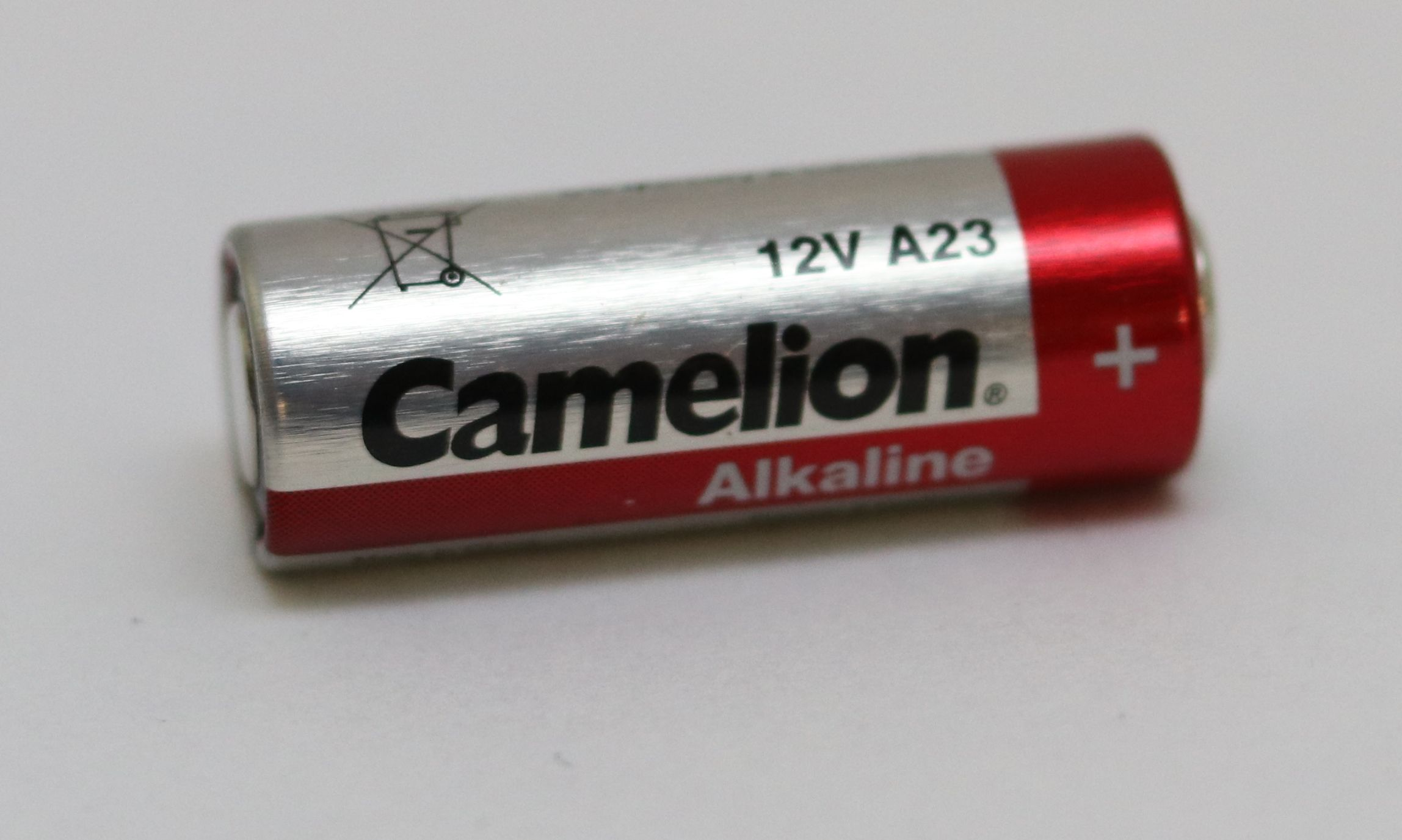 Bateria Camelion 12V A23. Srebrna bateria cylindryczna, czerwony pasek, czarny tekst.