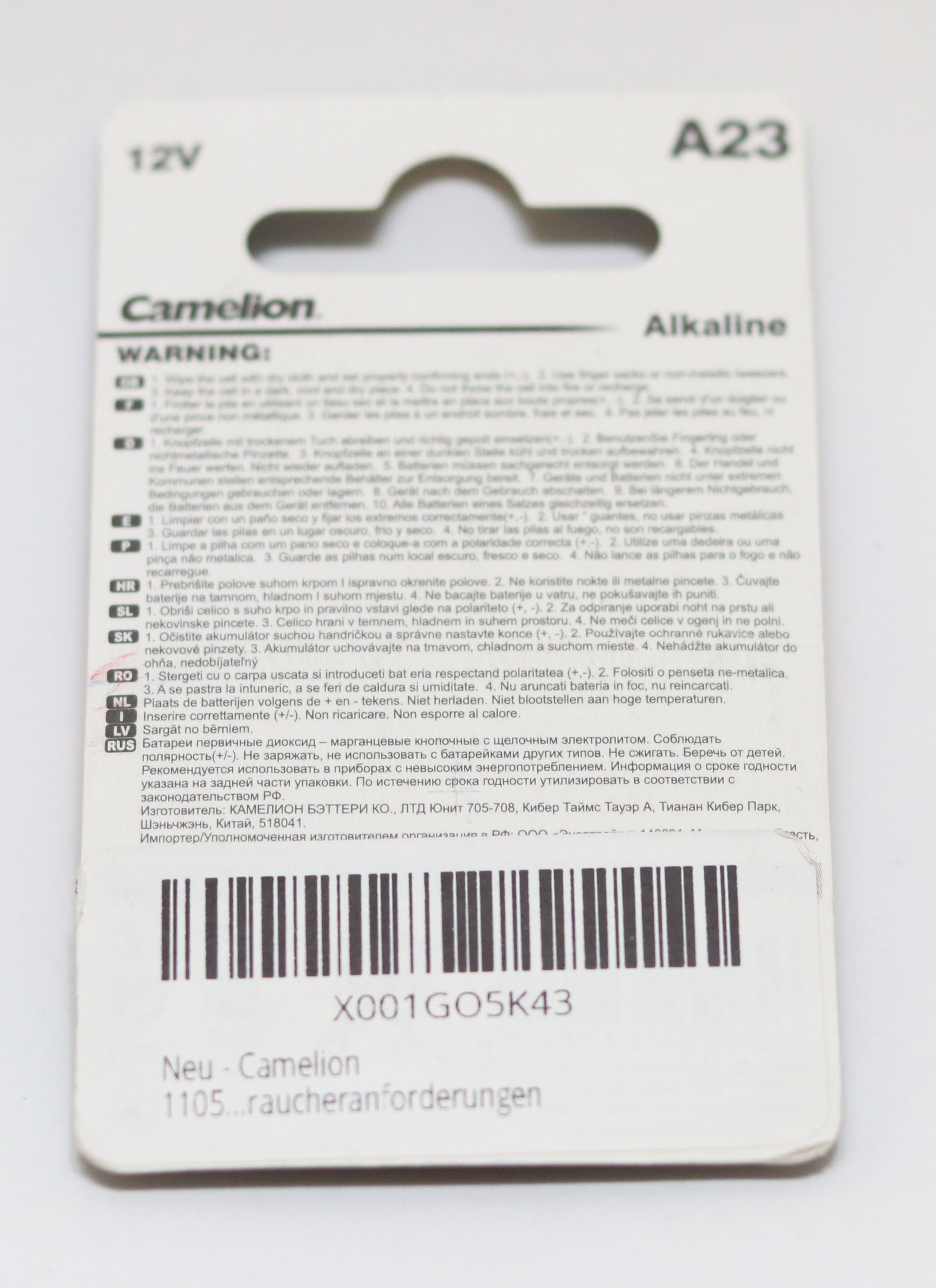 Biała kartka z tekstem ostrzegawczym dotyczącym baterii. Bateria alkaliczna A23 12V Camelion. Wielojęzyczne ostrzeżenia wydrukowane na papierze.