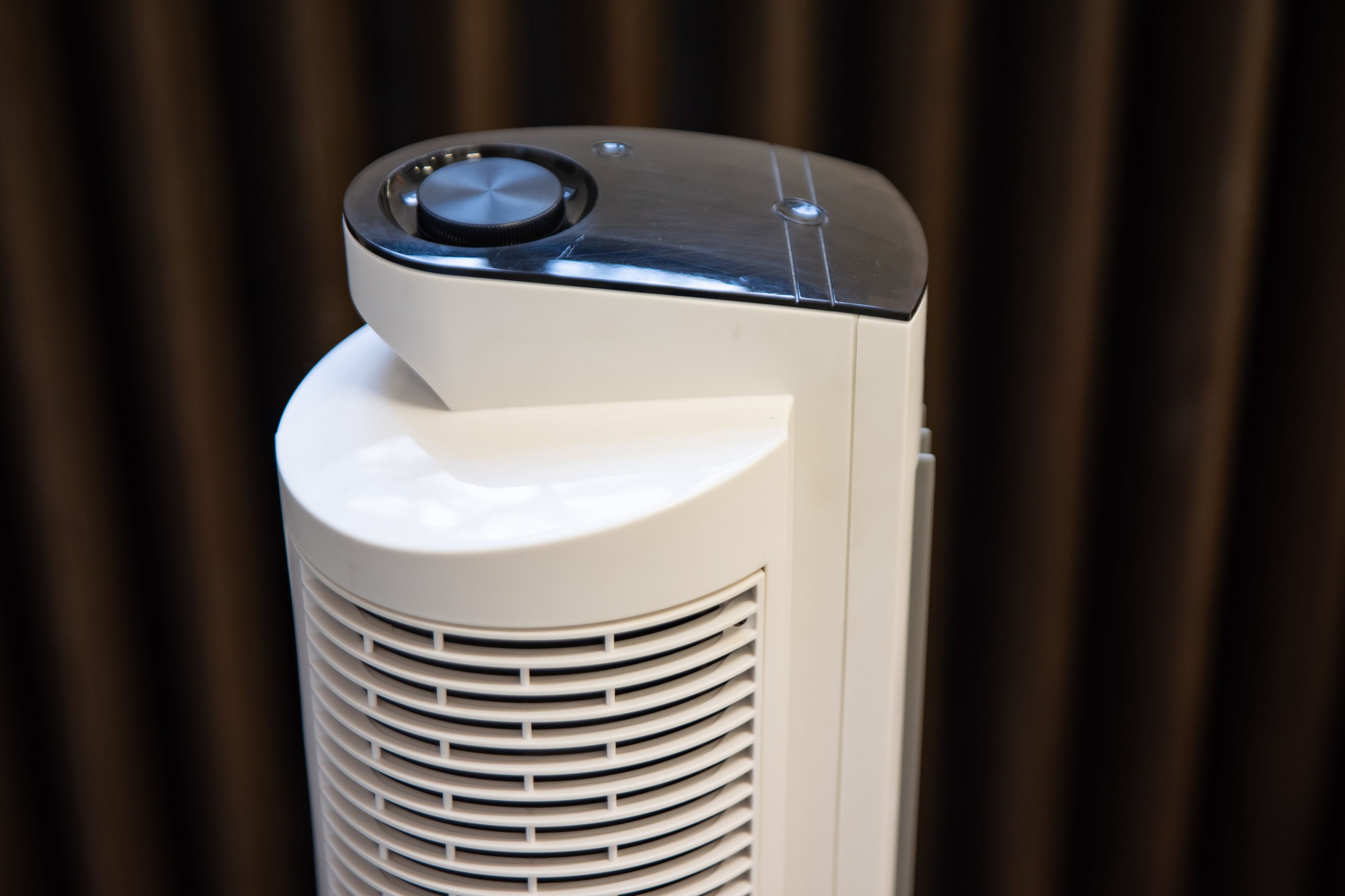Nahaufnahme eines weißen Ventilators mit schwarzem Bedienfeld. Der Hintergrund ist unscharf.