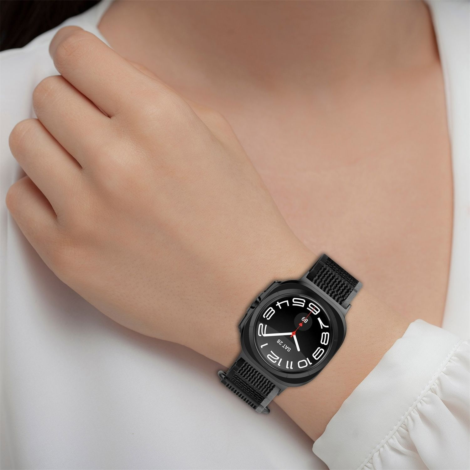 Handgelenk einer Person mit schwarzer Uhr. Die Uhr hat ein schwarzes Armband und ein rundes Zifferblatt.