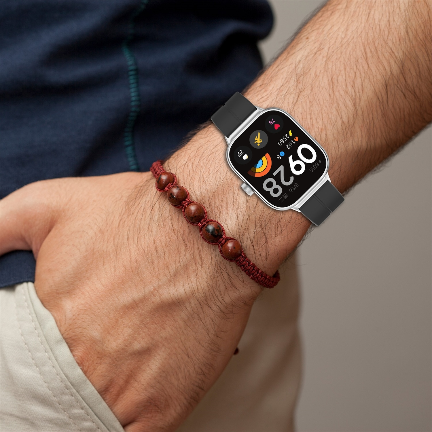Person trägt Smartwatch mit schwarzem Armband. Armband daneben. Weißes Zifferblatt.