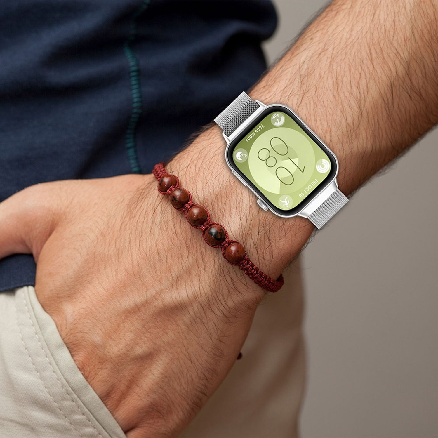 Mann mit silberner Smartwatch und rotem Perlenarmband. Die Uhr zeigt die Zeit an.