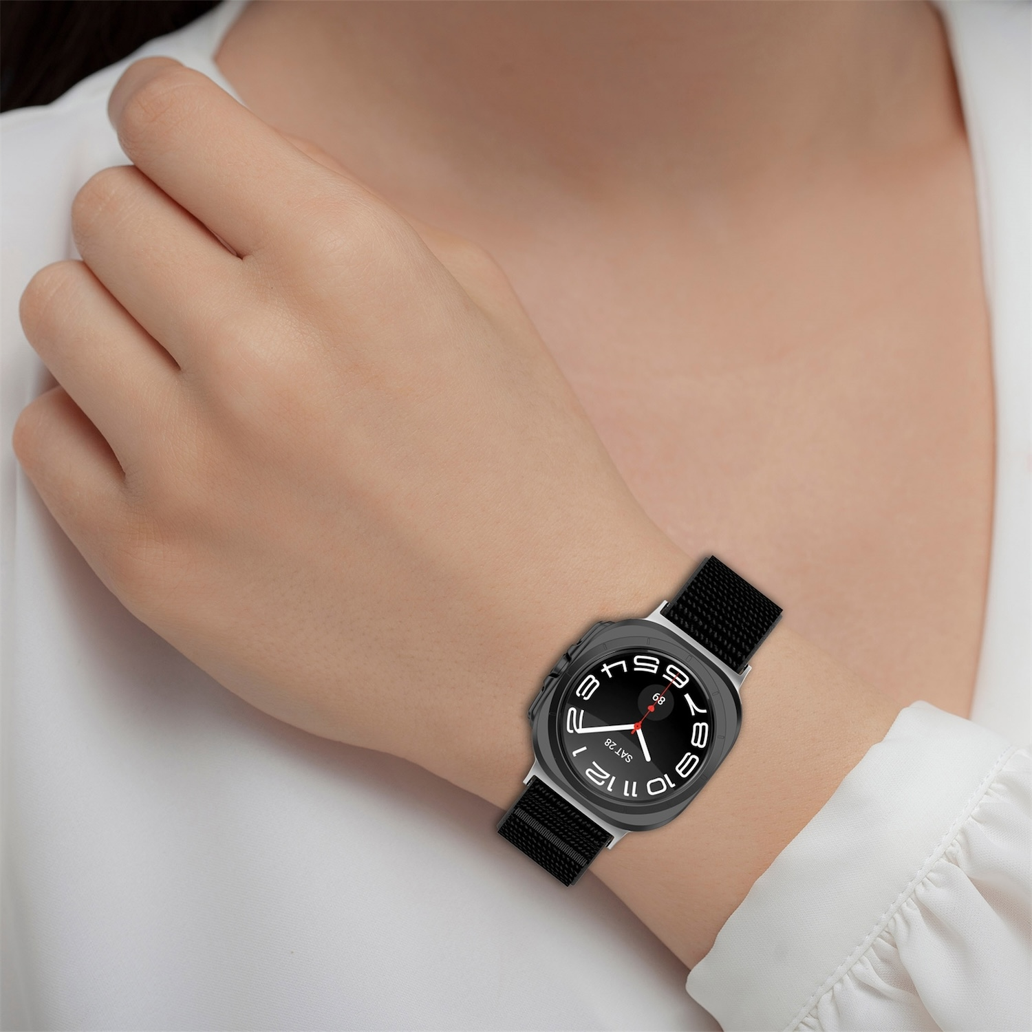 Das Handgelenk einer Person mit einer schwarzen Uhr mit weißen Zahlen und einem schwarzen Armband.