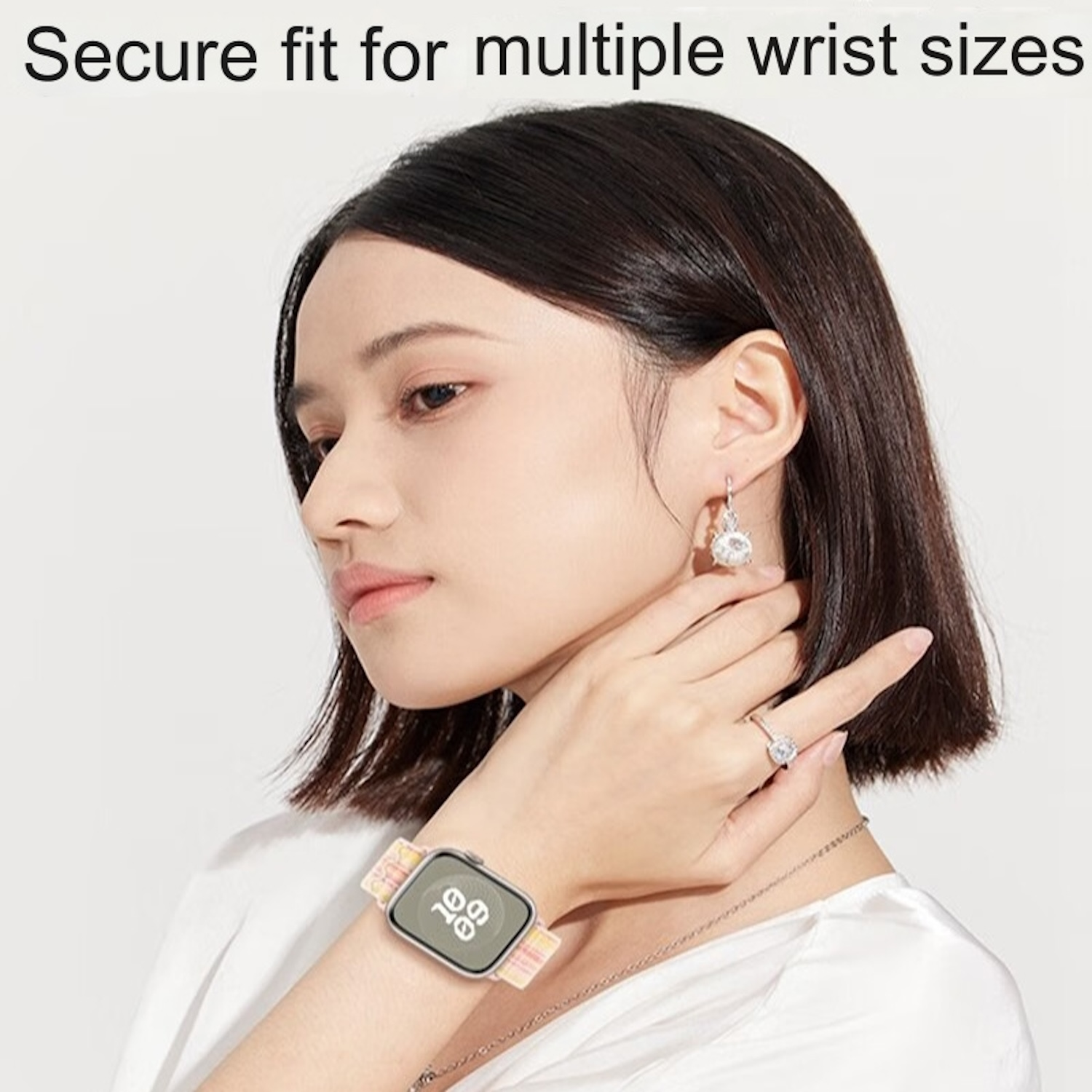 Eine Frau, die eine Uhr mit einem bunten Armband trägt. Sie trägt auch Ohrringe und einen Ring.