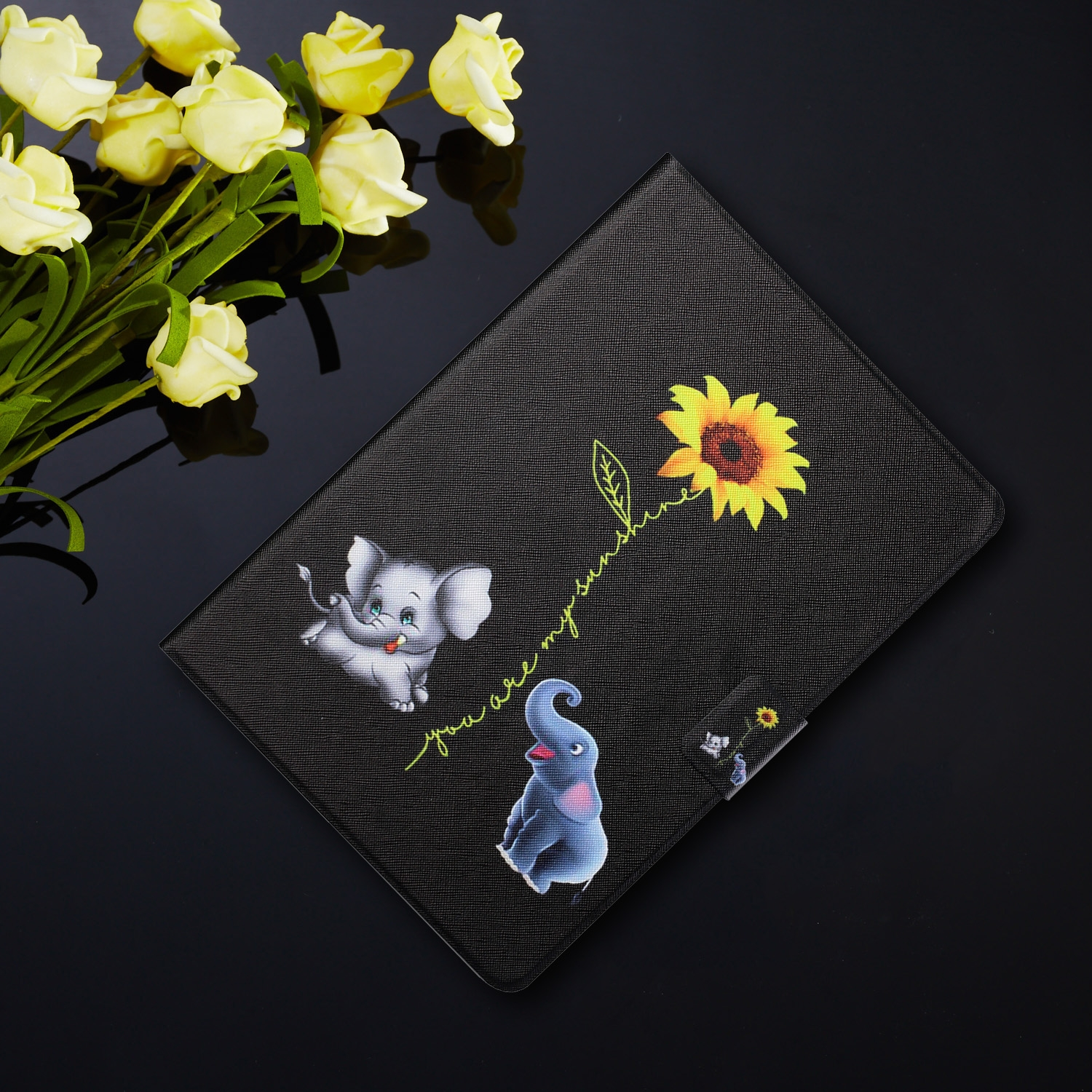 Schwarze Tablethülle mit Elefanten- und Sonnenblumenaufdruck. Gelbe Rosen, schwarzer Hintergrund.