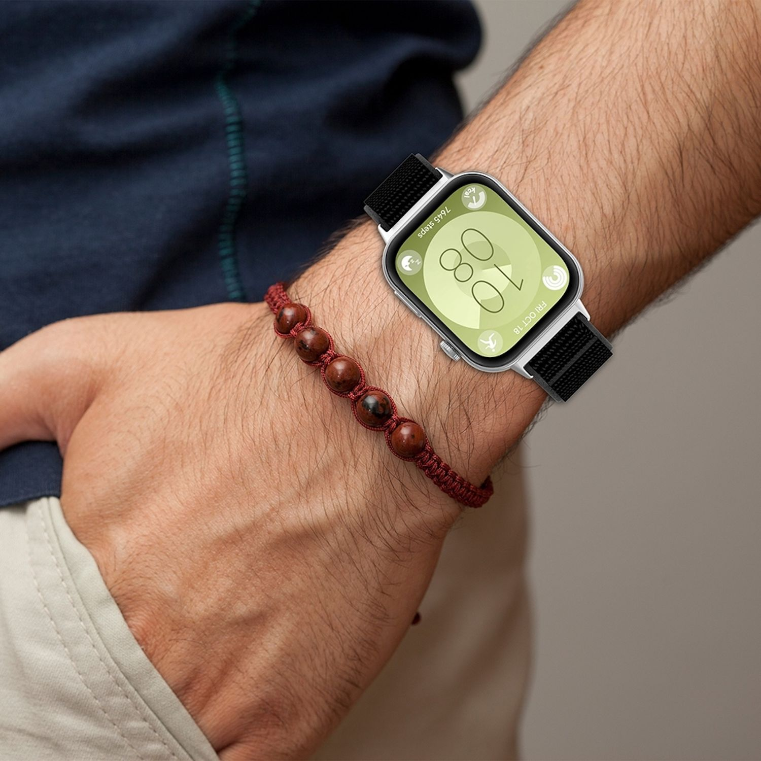 Handgelenk mit Uhr und Armband. Uhr hat schwarzes Band, zeigt Zeit.