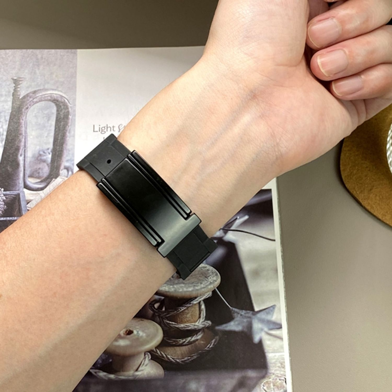 Das Handgelenk einer Person mit einem schwarzen Uhrenarmband.