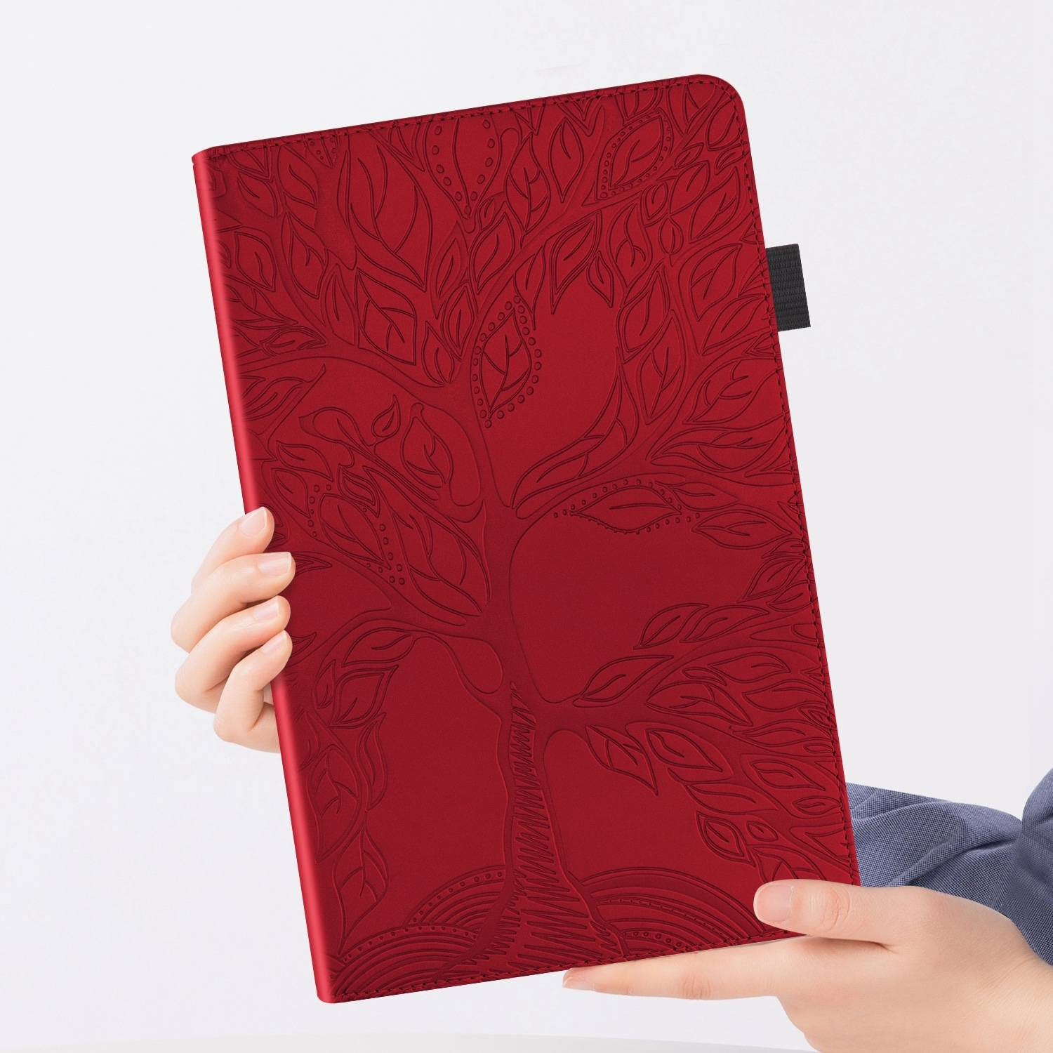 Funda de tableta roja, diseño de árbol, sujeta con manos sobre fondo blanco, toma de cerca.