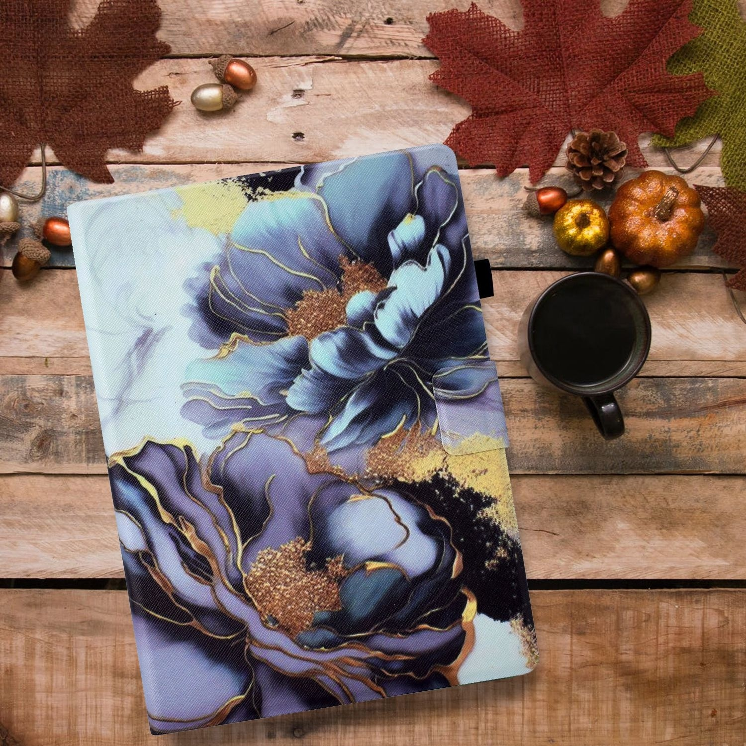 Tablet-Hülle mit floralem Design. Die Hülle liegt auf einem Holztisch mit Blättern und Tassen.
