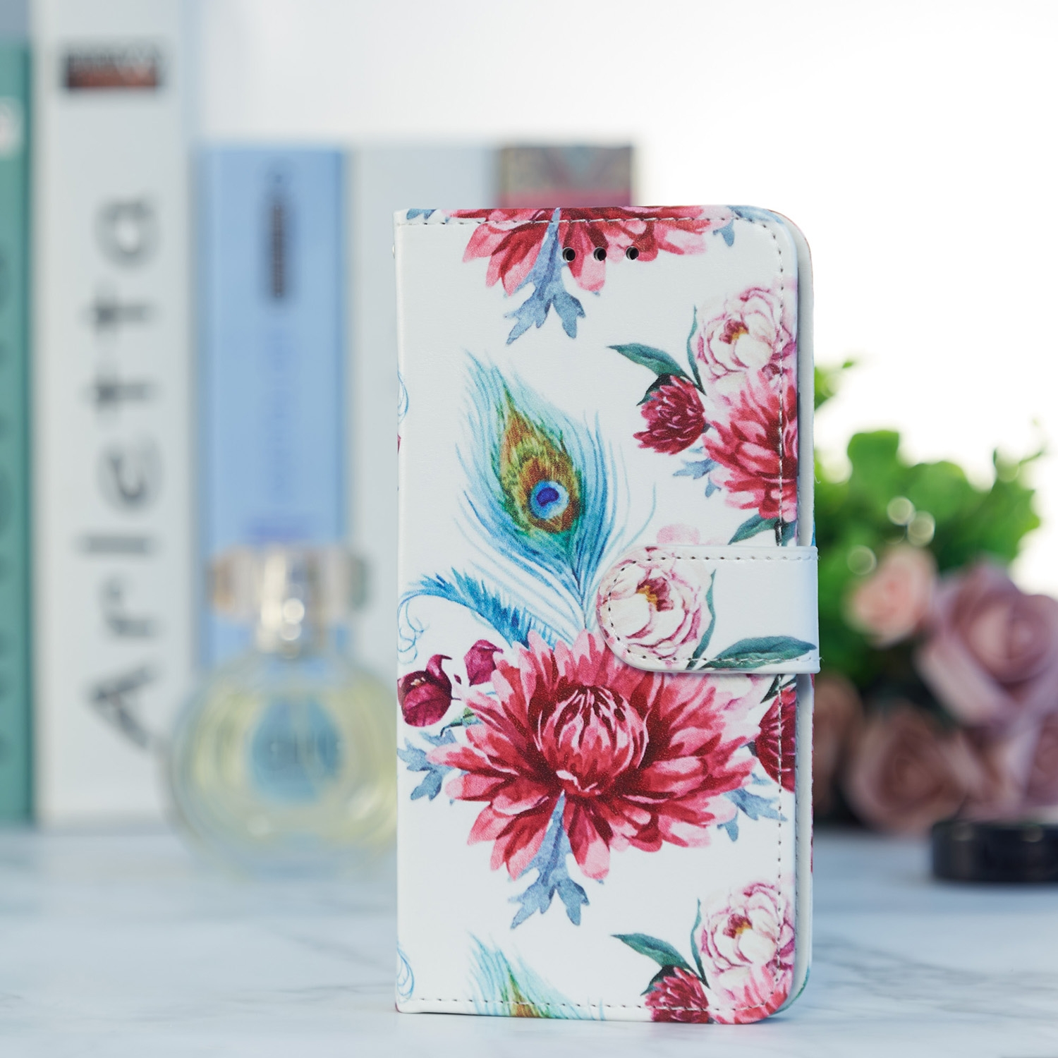 Eine weiße Handyhülle mit floralem Design, einer Pfauenfeder und einem Magnetverschluss.