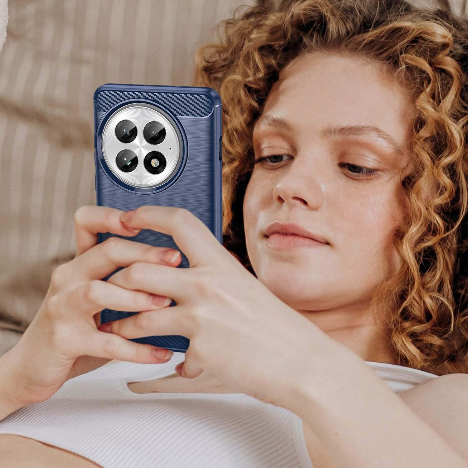 Eine Frau mit lockigem Haar hält eine blaue Handyhülle, um ein Foto auf ihrem Handy zu machen.