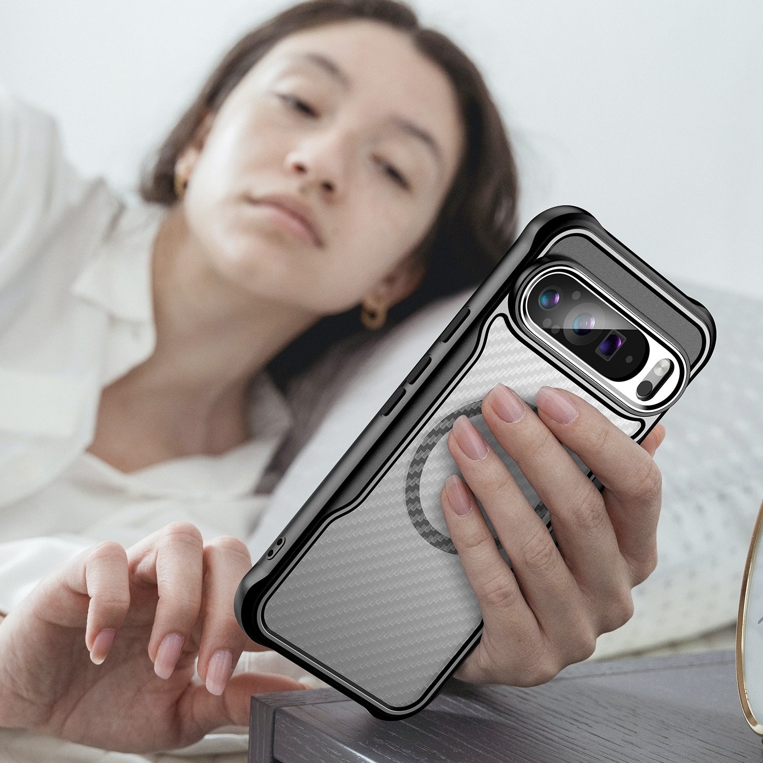 Mujer en cama sosteniendo un teléfono con funda transparente, mostrando un patrón gris.