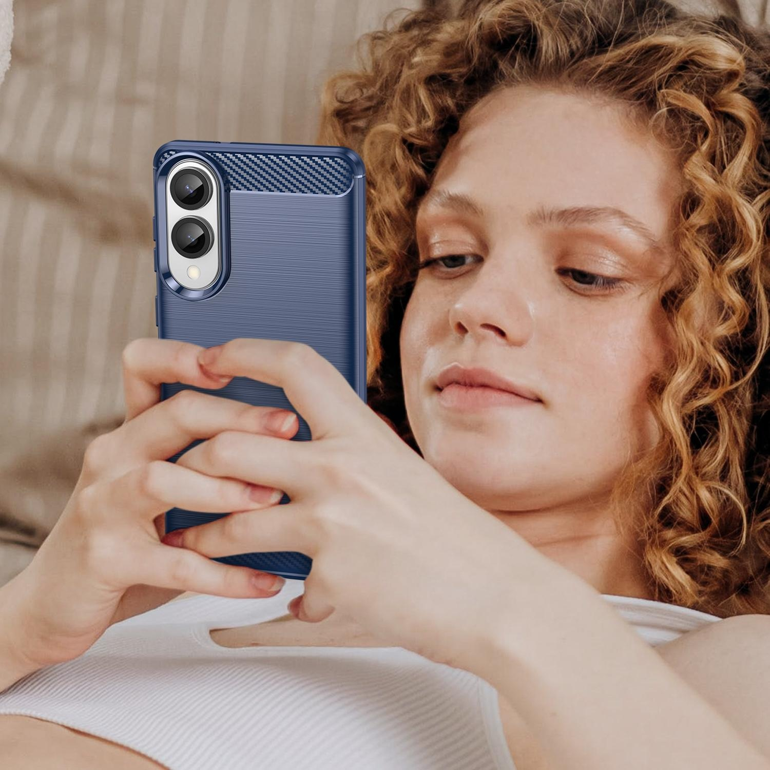 Eine Frau hält ein blaues Telefon mit Hülle und schaut auf den Bildschirm.