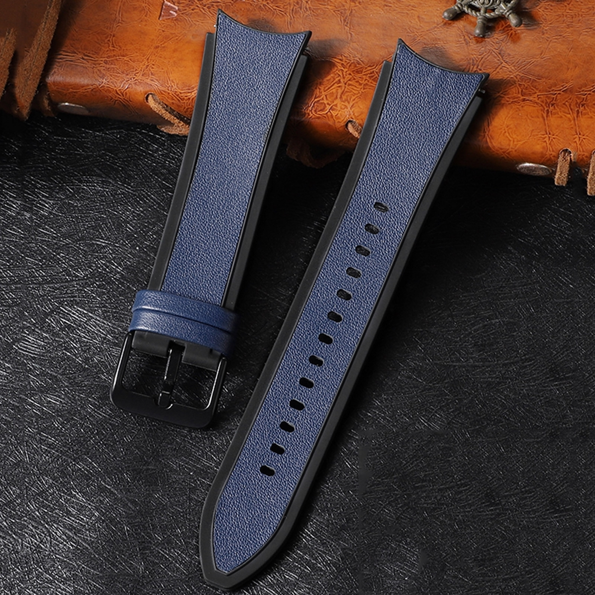 Zwei Uhrenarmbänder. Blau und schwarz mit schwarzer Schnalle. Auf brauner Lederoberfläche.