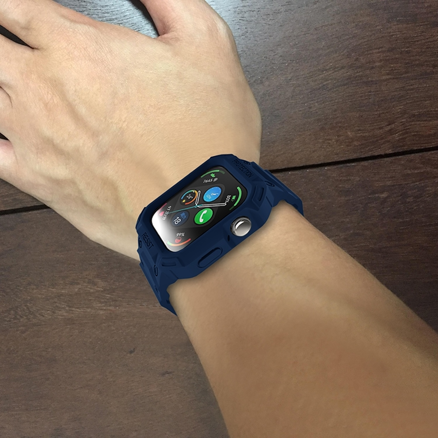 Eine Hand, die eine blaue Smartwatch trägt, auf einer braunen Holzoberfläche.