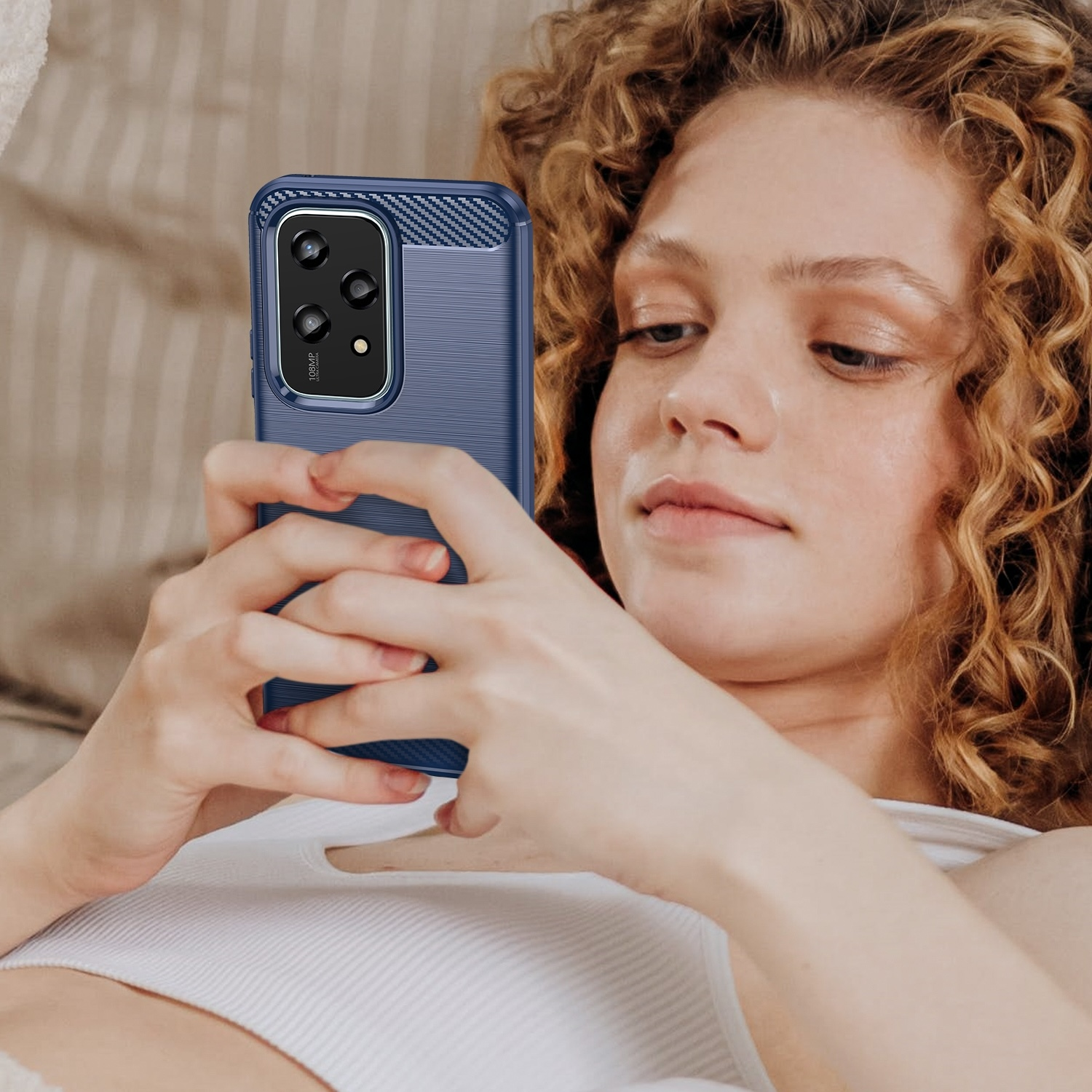 Frau, die eine blaue Handyhülle hält und auf das Handy schaut.