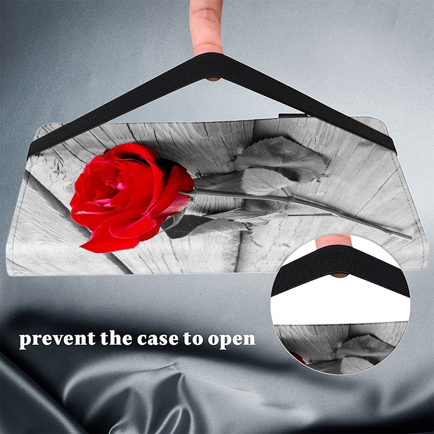 Tablet-Hülle mit roter Rose und schwarzem Riemen auf grauer Oberfläche, mit einer Hand, die den Riemen hält.
