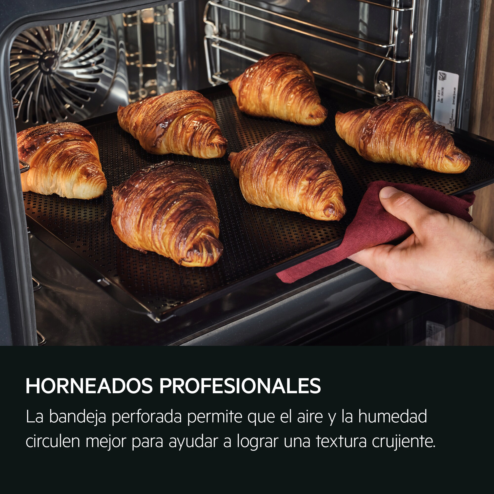 Cruasanes en una bandeja negra, sacados del horno con un paño rojo.