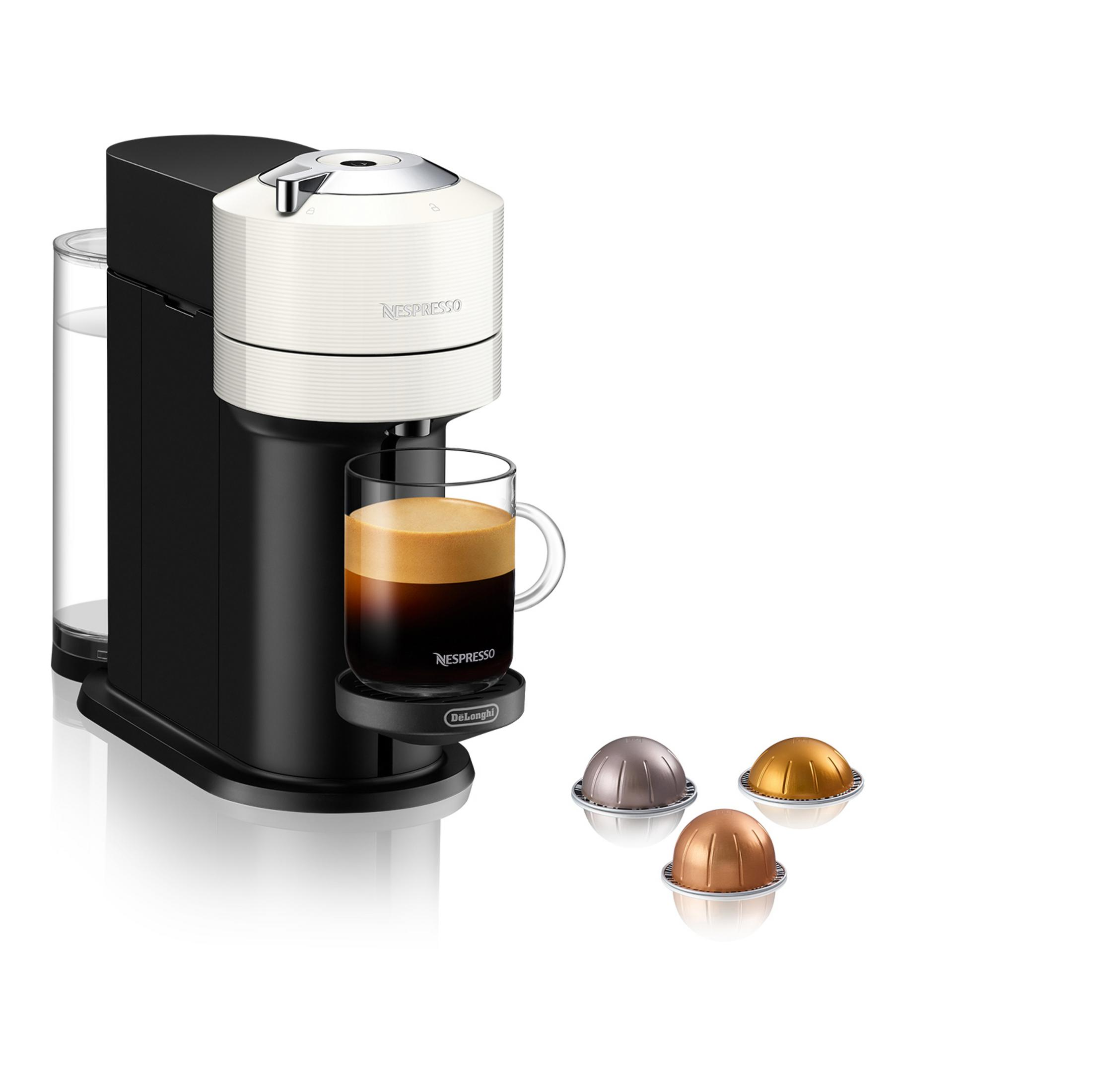 Una cafetera Nespresso en blanco y negro, preparando una taza de espresso, con cápsulas de café al lado.