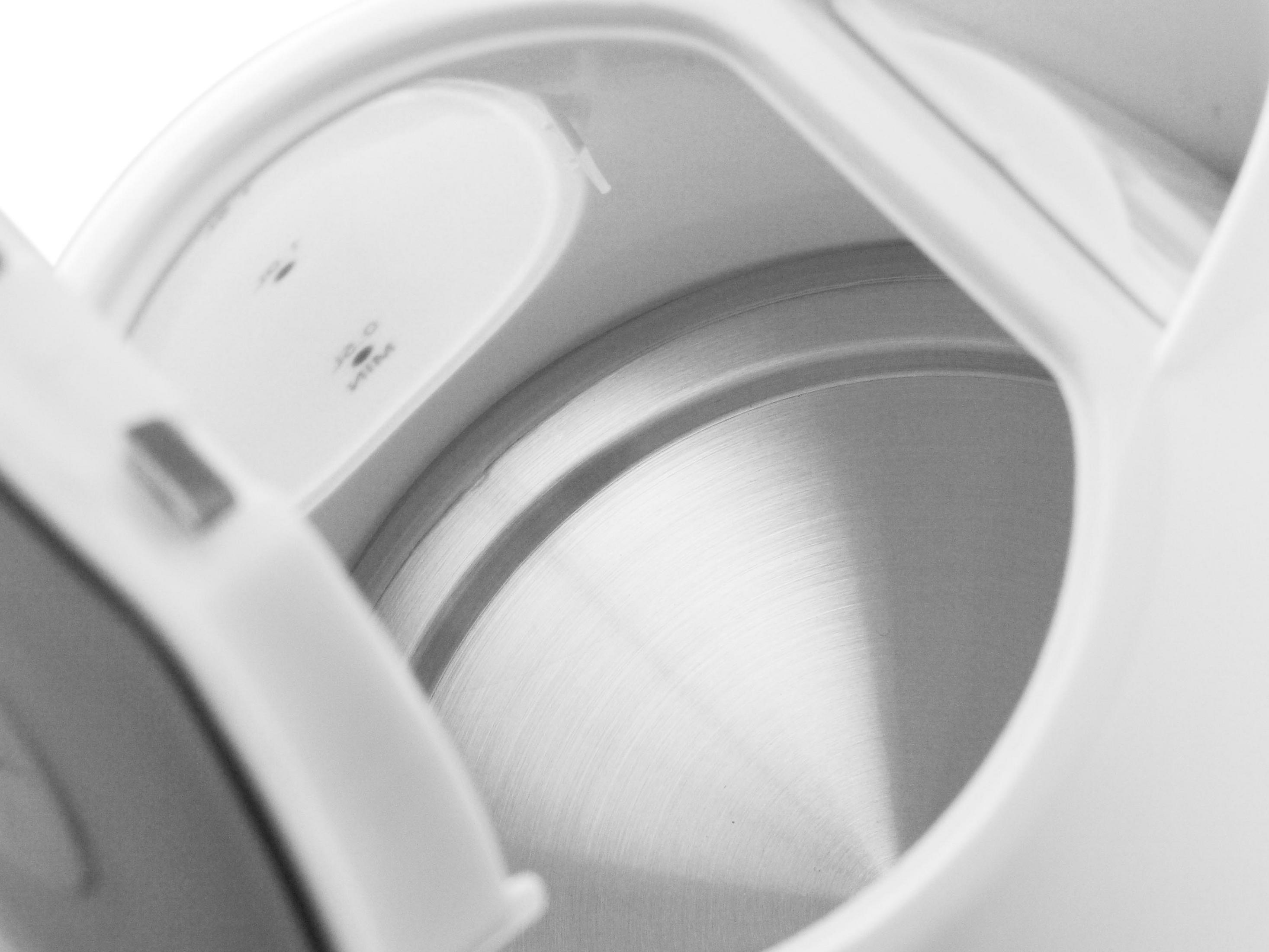 Zbliżenie wnętrza białego czajnika elektrycznego z otwartą pokrywą, pokazujące wnętrze.