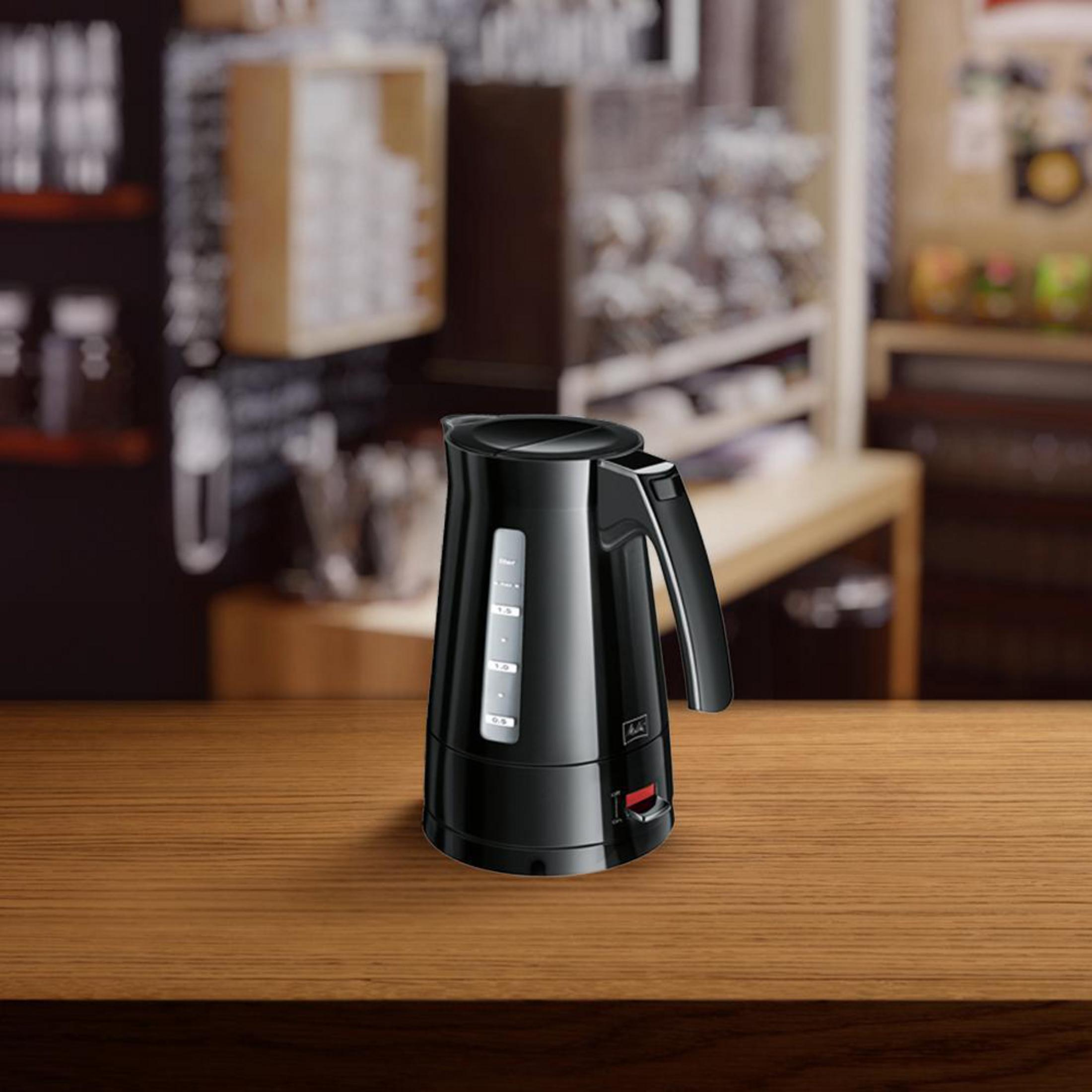 Hervidor eléctrico negro Melitta sobre mesa de madera. Fondo borroso de café.