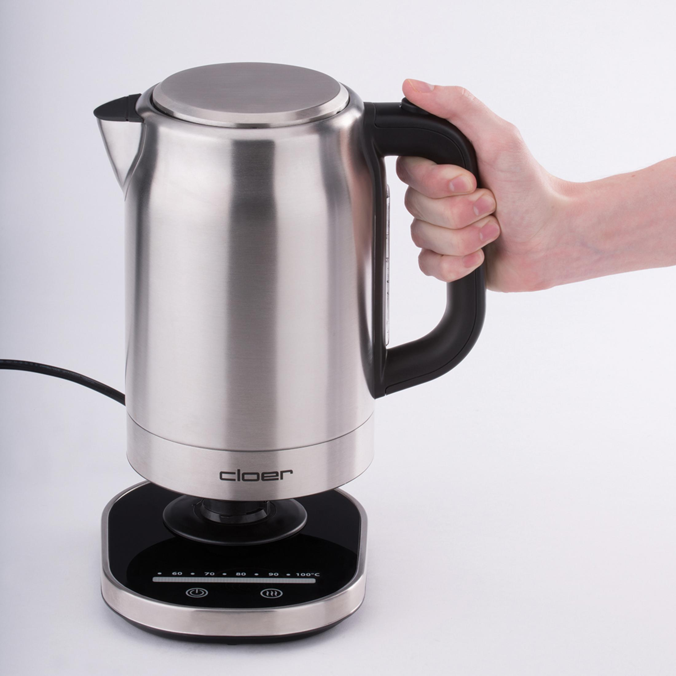 Srebrny czajnik z czarnym uchwytem. Dłoń trzymająca uchwyt. Białe tło.