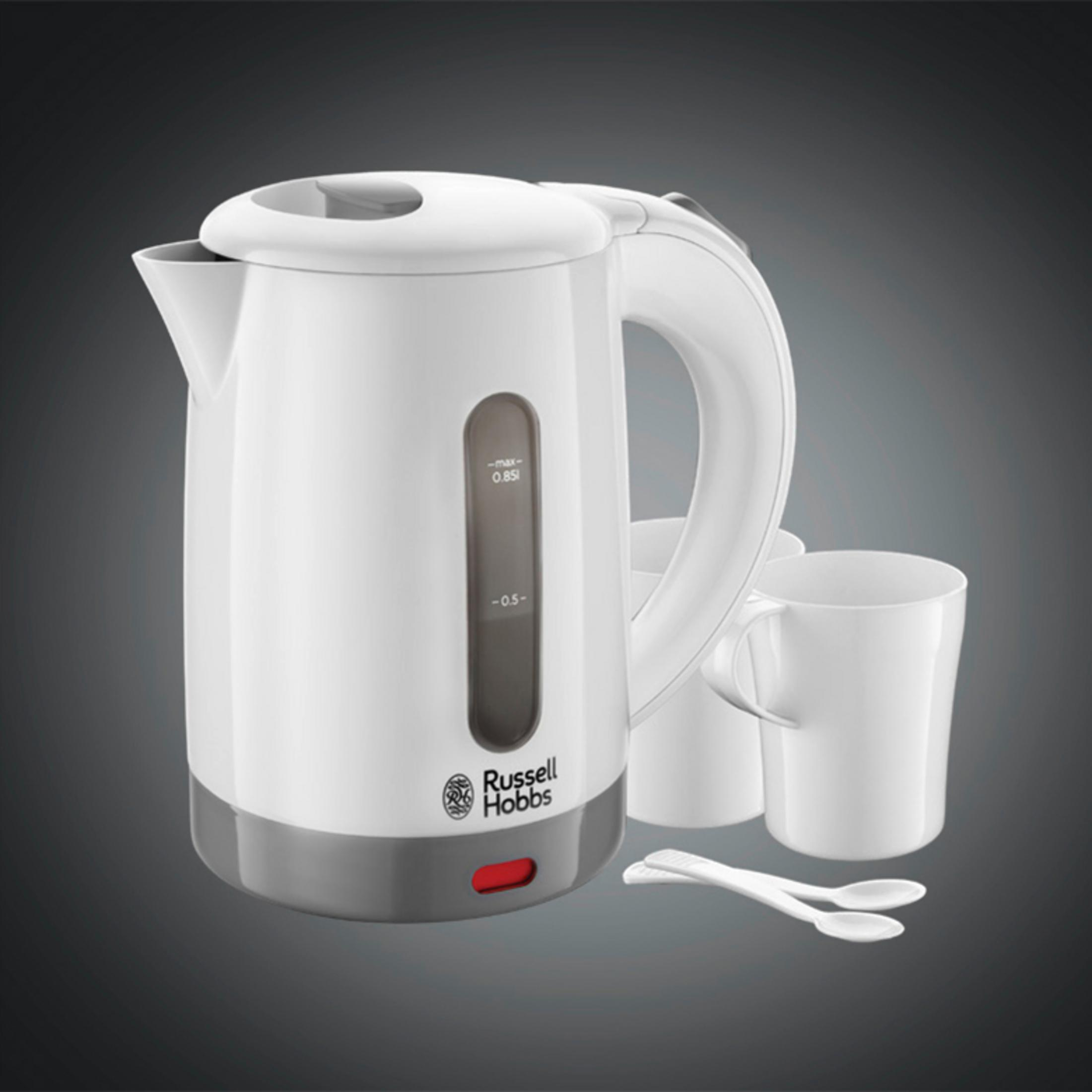 Biały czajnik elektryczny z szarą podstawą i przezroczystym wskaźnikiem poziomu wody. W pobliżu są dwie filiżanki i łyżki.