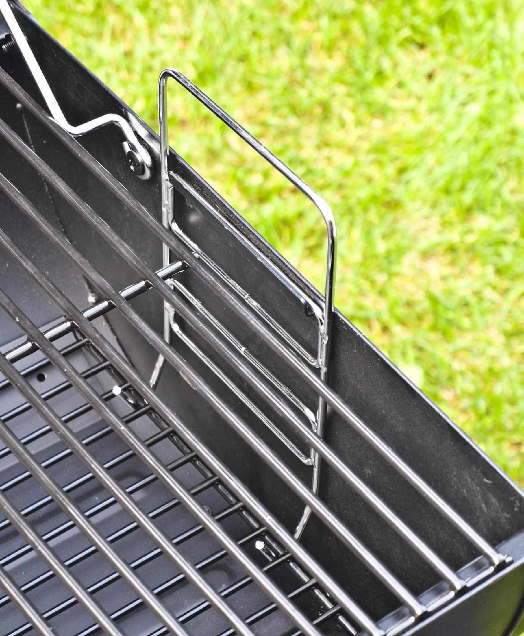 Nahaufnahme eines schwarzen Grills. Der Grill hat parallele Stäbe und einen silbernen Griff.