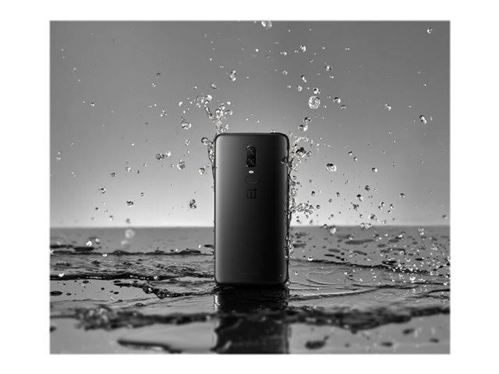 Schwarzes Smartphone mit Wasserspritzern, Rückansicht, schwarzer Hintergrund.