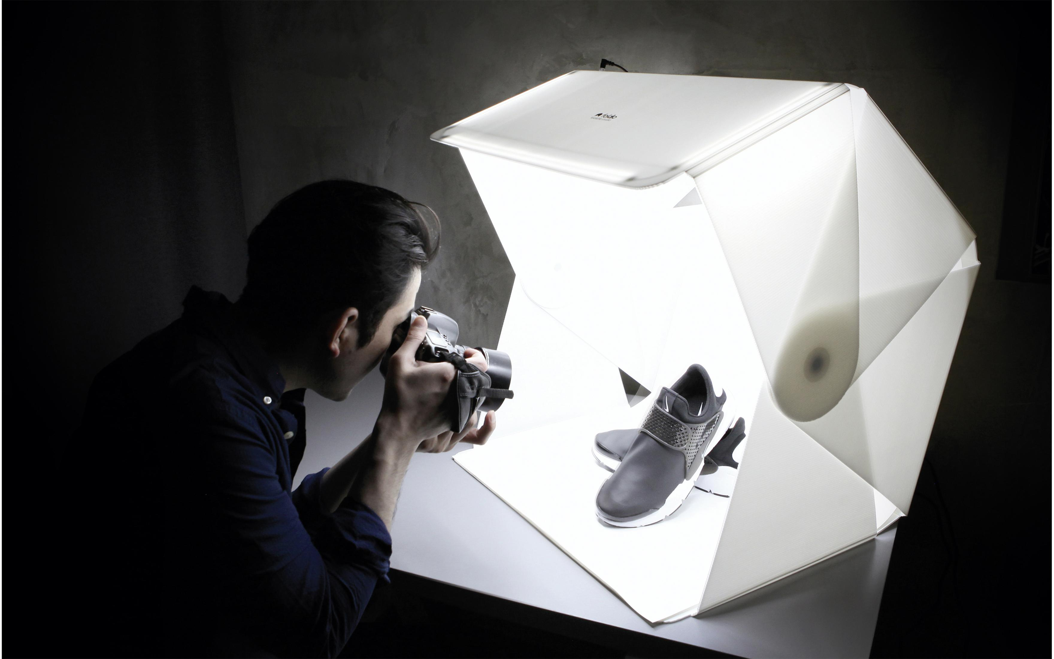 Person fotografiert Schuhe in einer weißen Produktfotografie-Lichtbox.