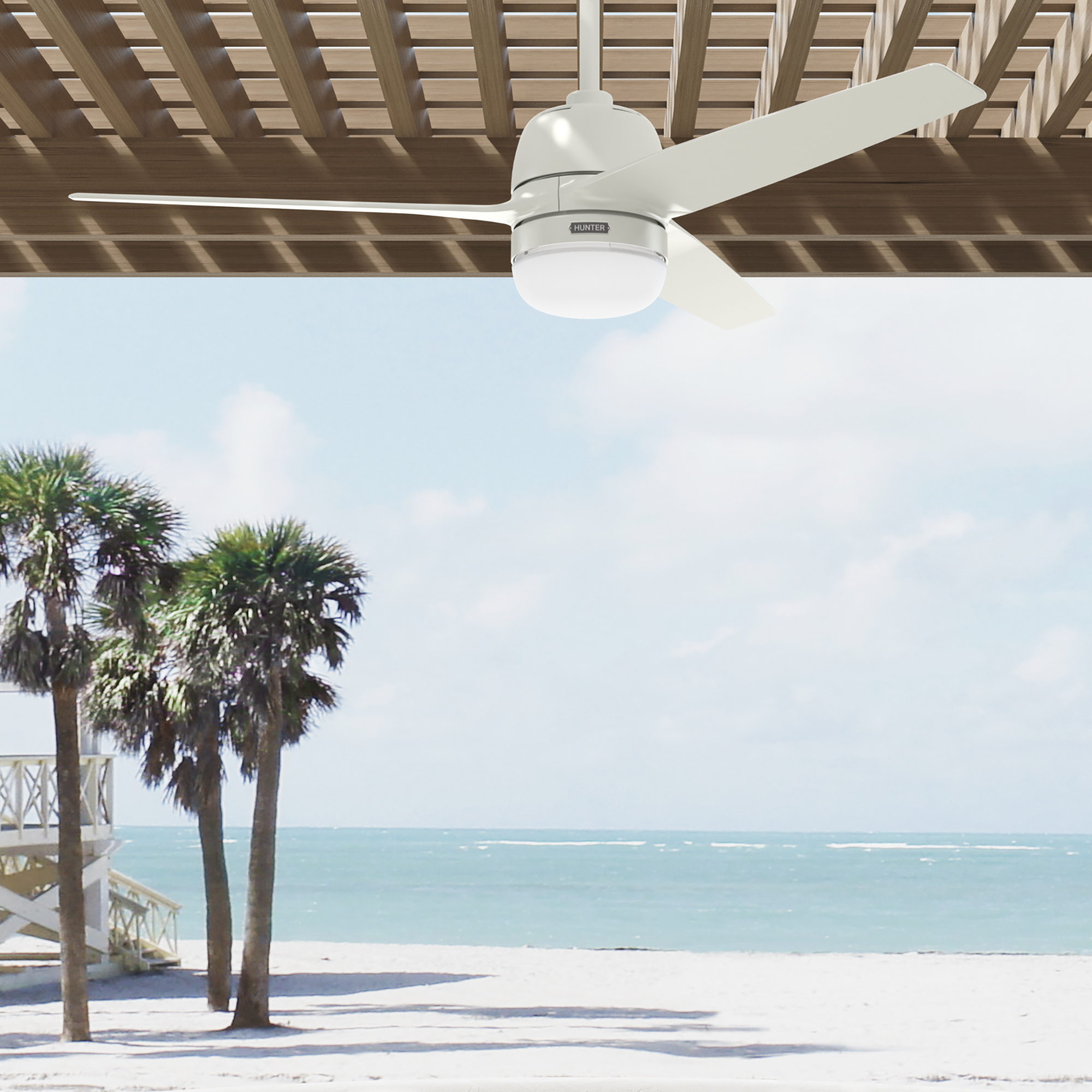Ein weißer Deckenventilator ist montiert. Palmen sind im Hintergrund sichtbar. Eine Strandszene mit blauem Himmel.