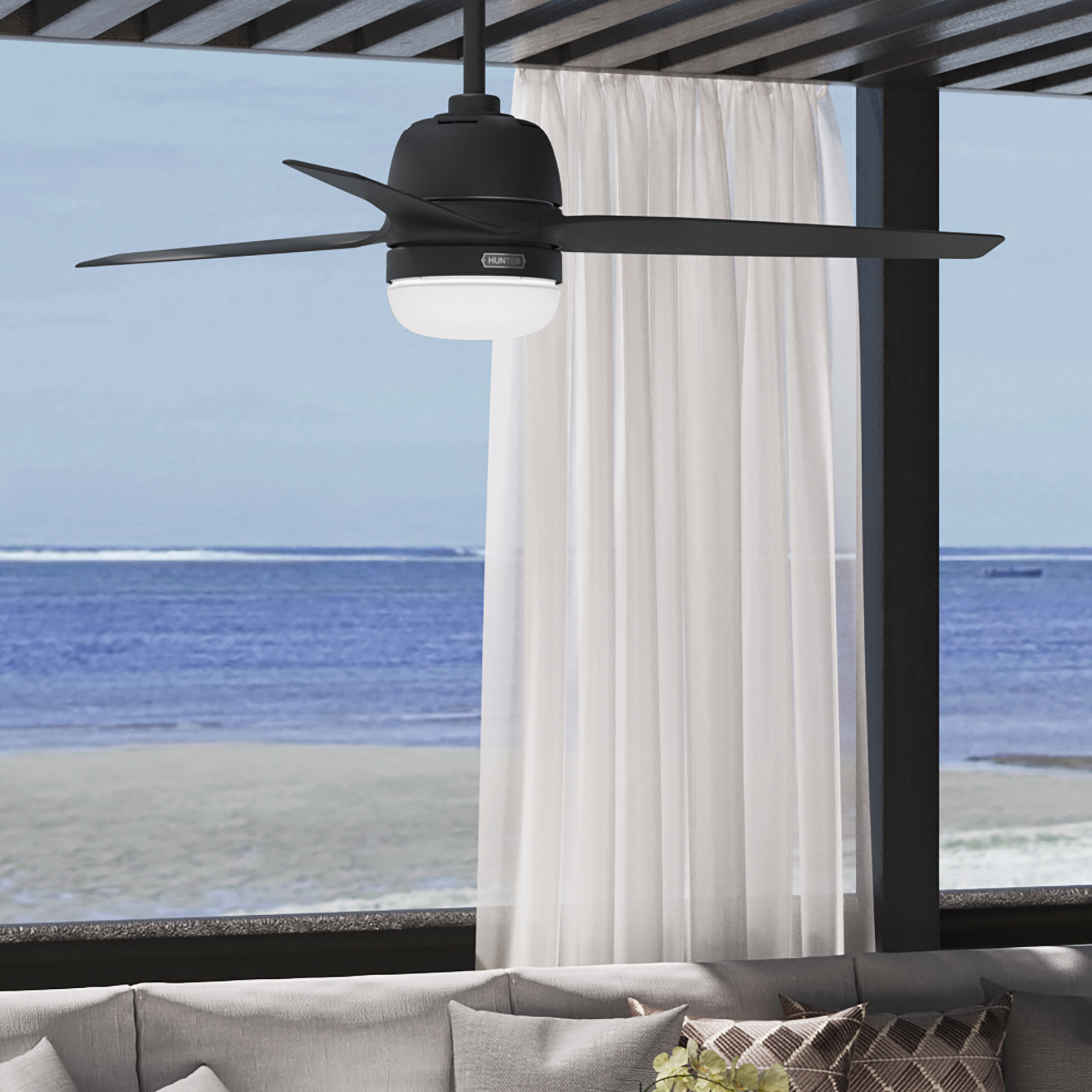 Schwarzer Deckenventilator im Freien. Blick auf einen Strand und das Meer.