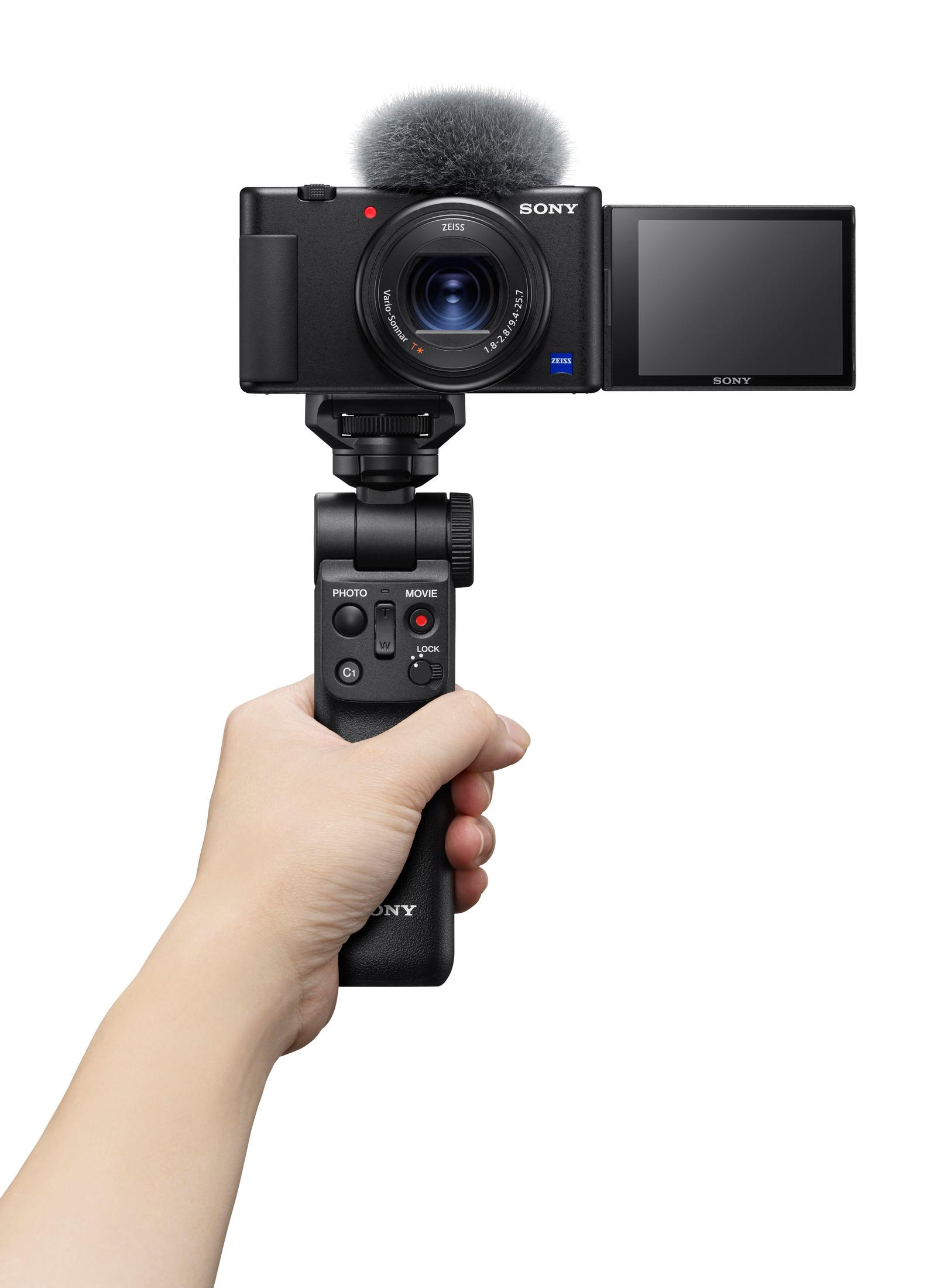 Zwarte camera met microfoon, vastgehouden door een hand, op een statief.