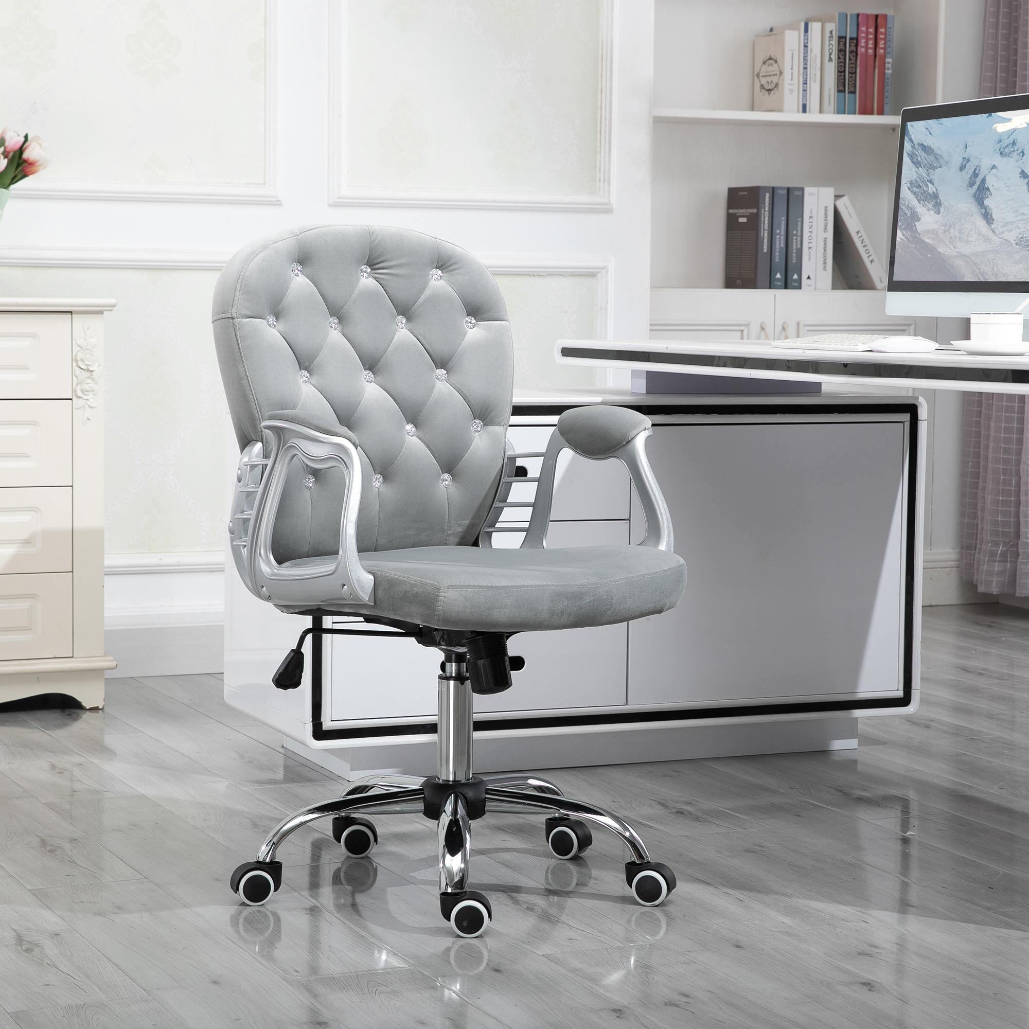 Silla de oficina gris con respaldo acolchado con diamantes y brazos plateados. Ubicada en una oficina moderna con un escritorio blanco.