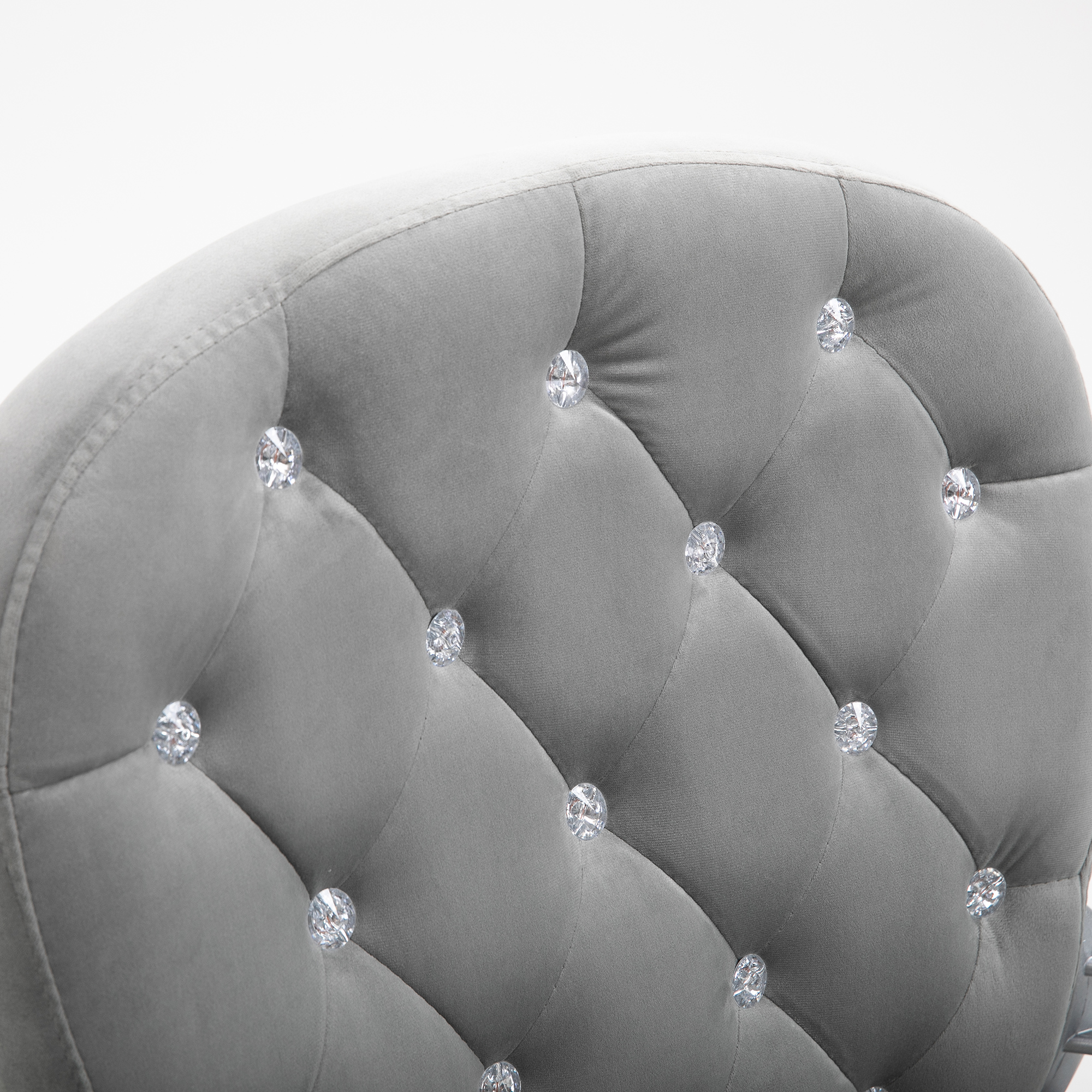 Primer plano de la parte trasera de una silla de oficina gris con acolchado en forma de diamante y botones de cristal.