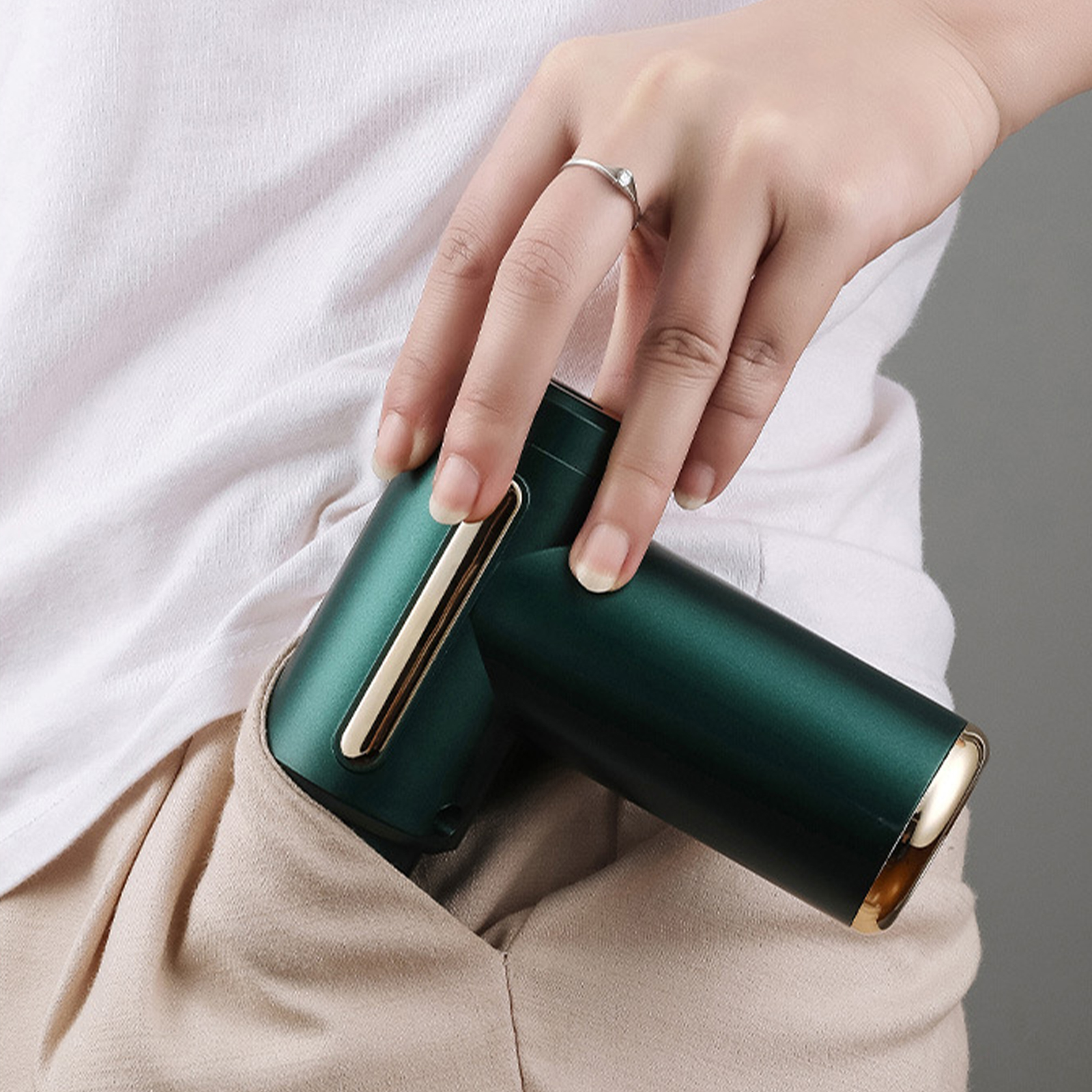Grüner Mini-Staubsauger in einer Tasche. Weißes T-Shirt und khakifarbene Hose.