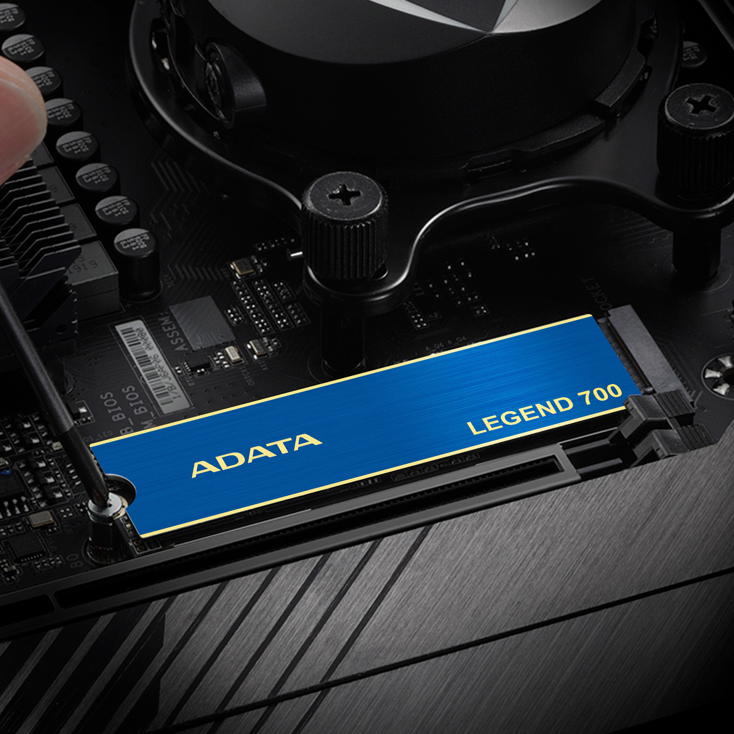 Ręka instalująca niebieski ADATA Legend 700 SSD na płycie głównej.