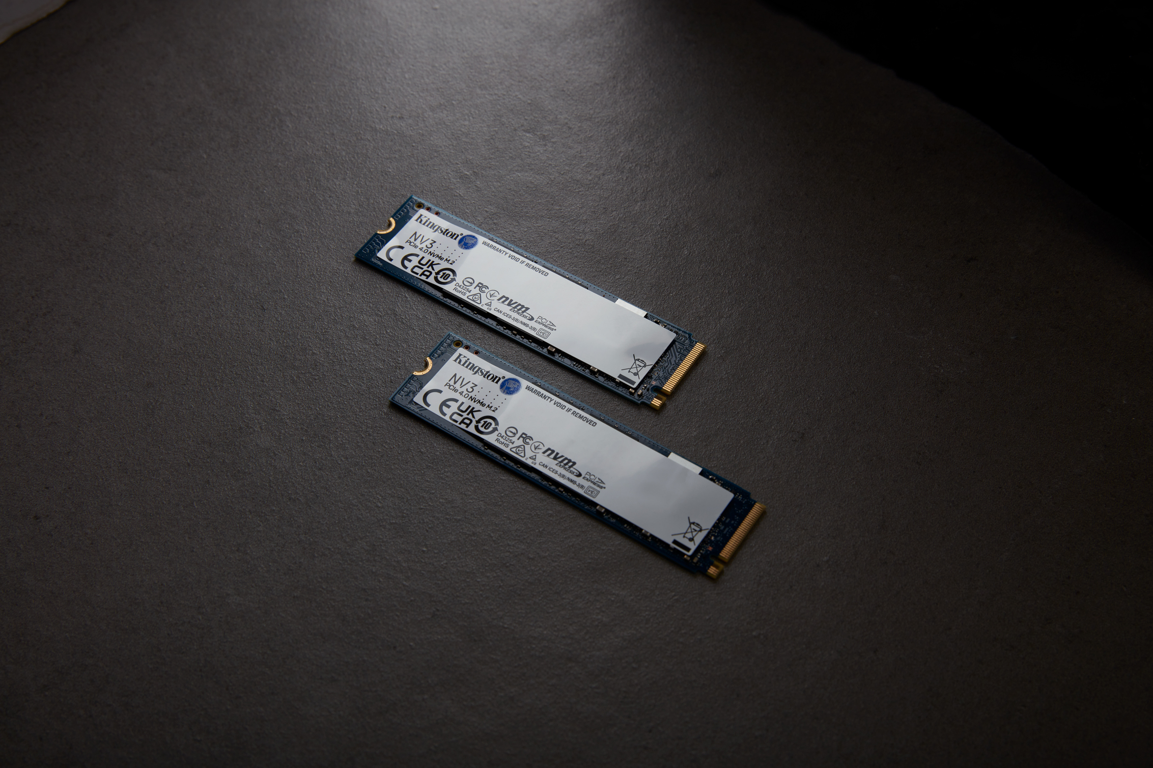 Dos SSD M.2 sobre una superficie oscura. Son azules y blancos con conectores dorados. Marca Kingston.
