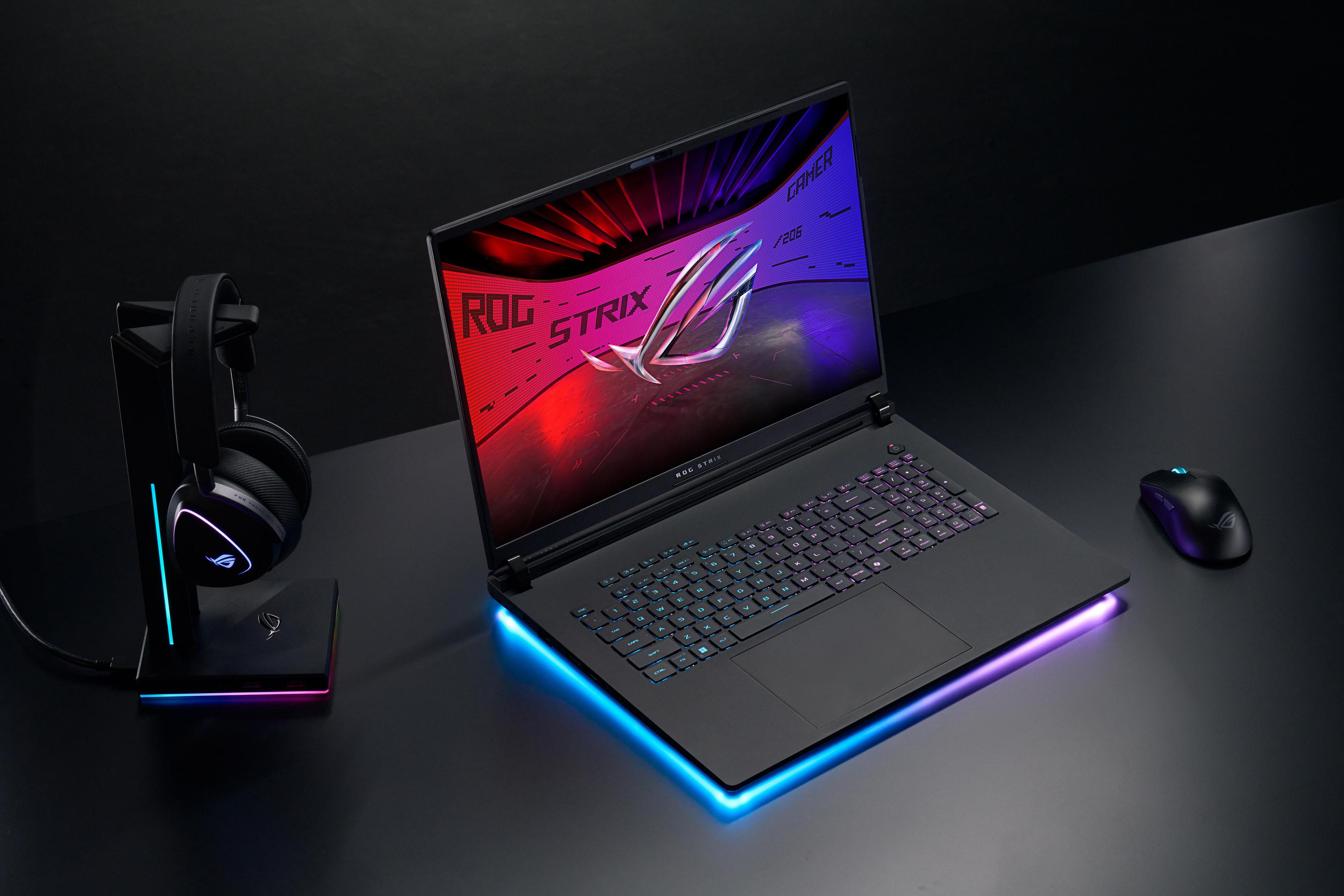 Gaming-Laptop auf dem Schreibtisch. Schwarzes Design mit ROG Strix Logo. Kopfhörer und Maus daneben.