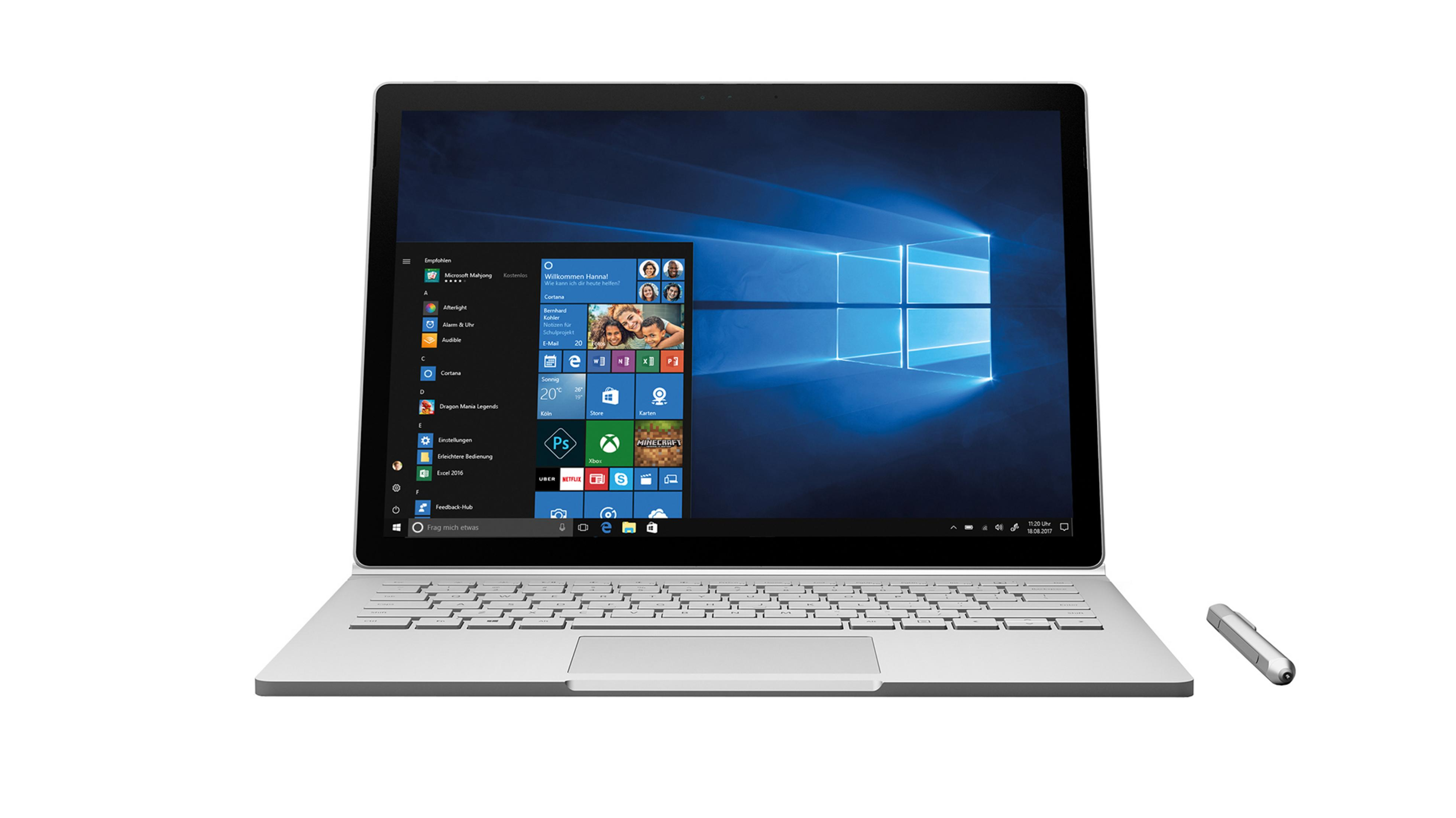 Ein silbernes Laptop ist geöffnet und zeigt die Windows-Oberfläche. Ein Stift liegt daneben. Weißer Hintergrund.