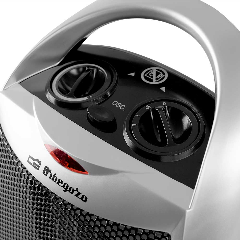 Elementy sterujące srebrno-czarnego przenośnego grzejnika. Pokrętła i czerwona lampka kontrolna.