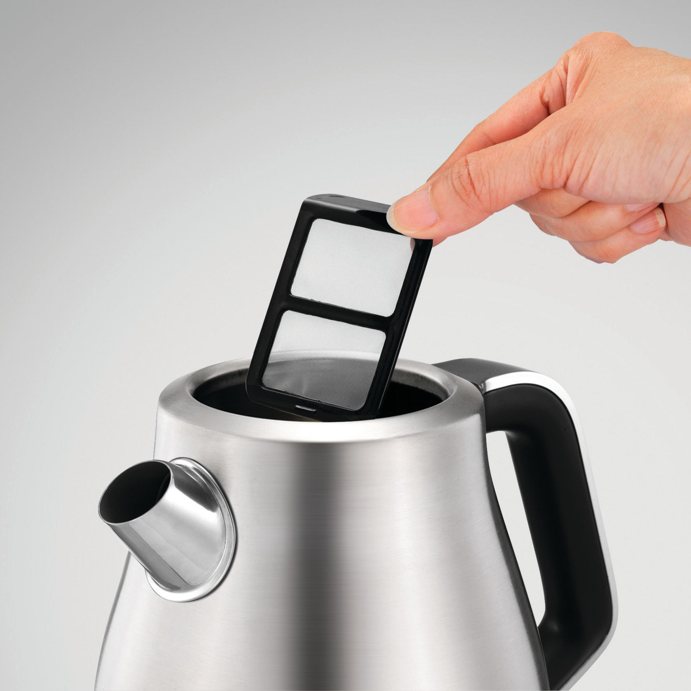 Ręka wyjmująca czarny filtr ze środka czajnika ze stali nierdzewnej.