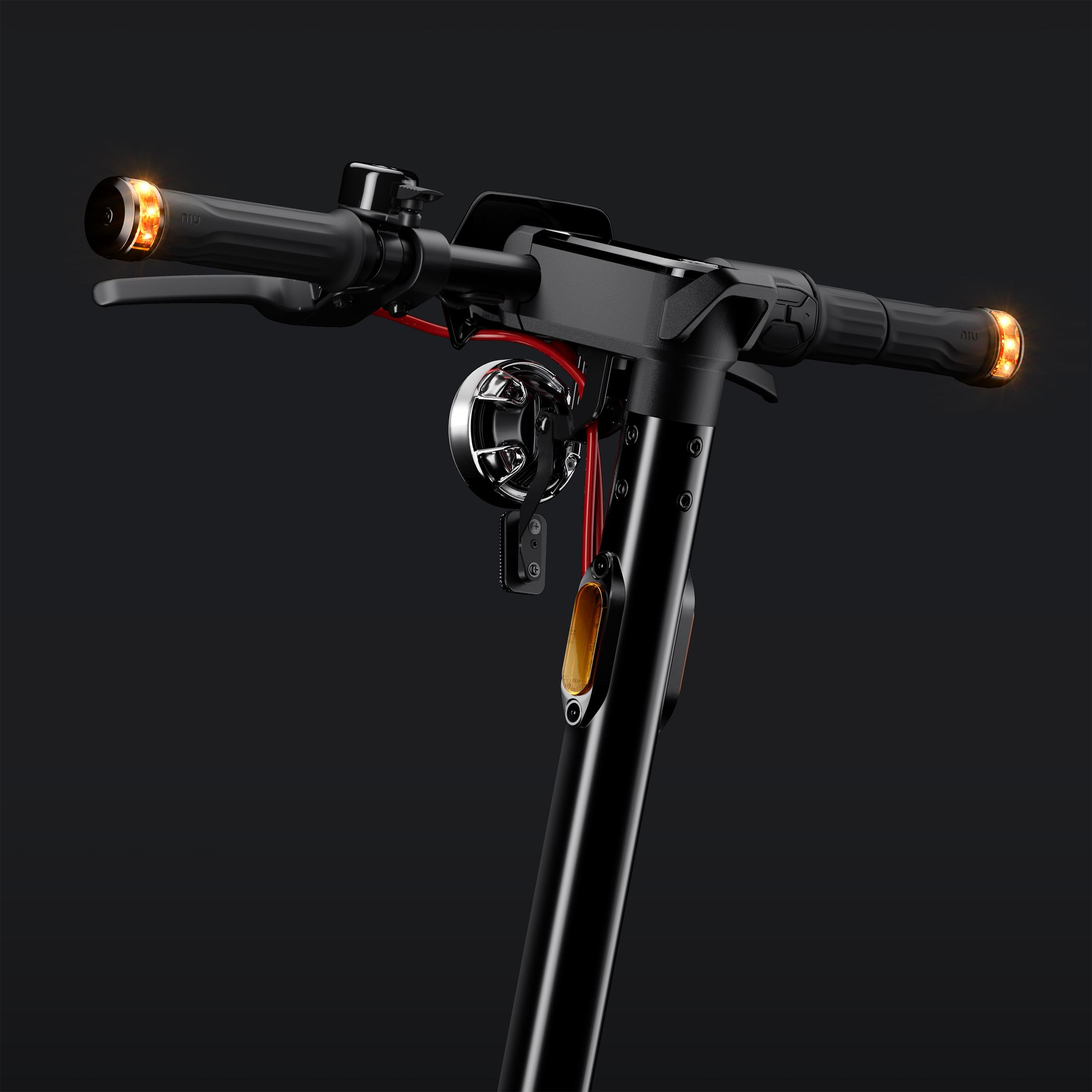 Zbliżenie na kierownicę hulajnogi elektrycznej. Czarna z czerwonymi akcentami, dzwonkiem i światłami.