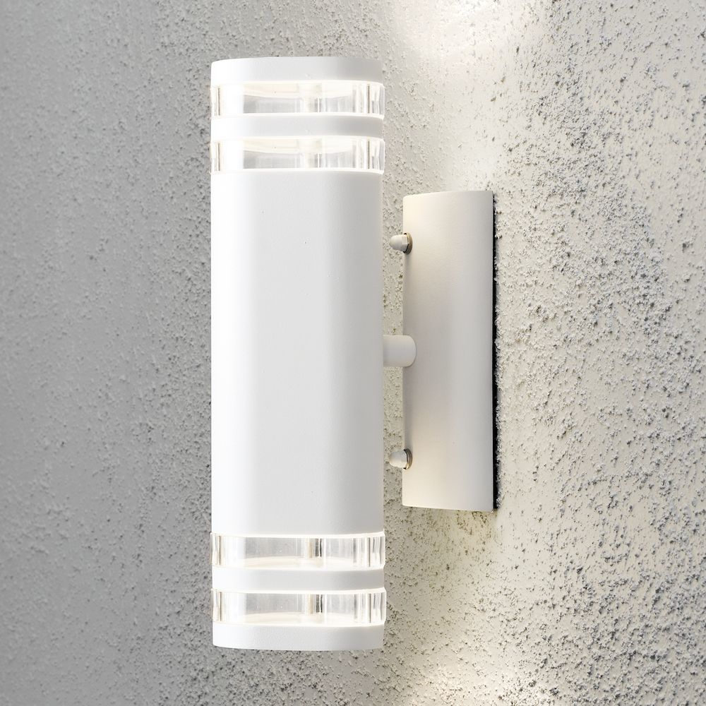 Apparecchio di illuminazione bianco montato su un muro strutturato. L'apparecchio ha sezioni trasparenti.