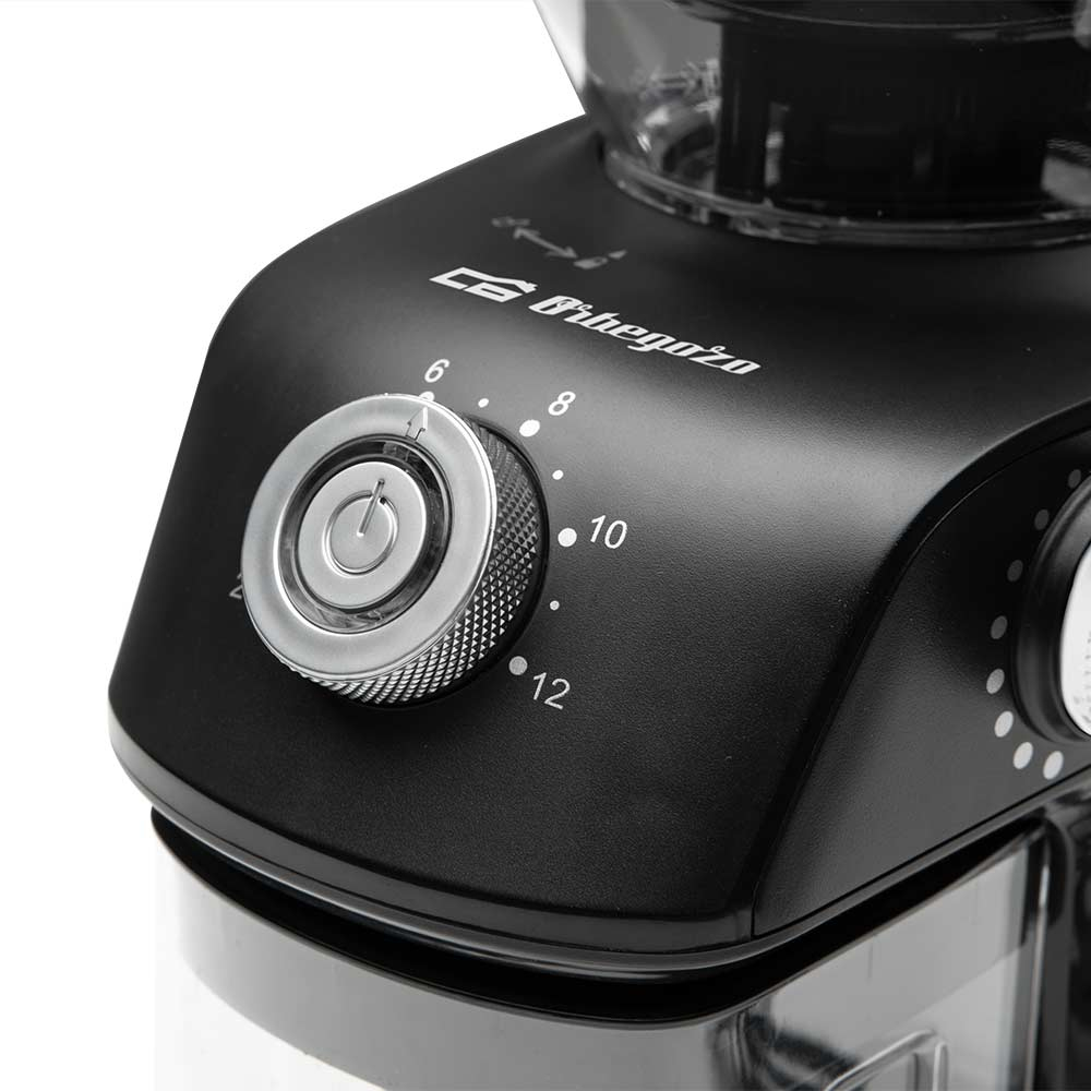 Zbliżenie czarnego młynka do kawy z pokrętłem, numerami i przezroczystym pojemnikiem.