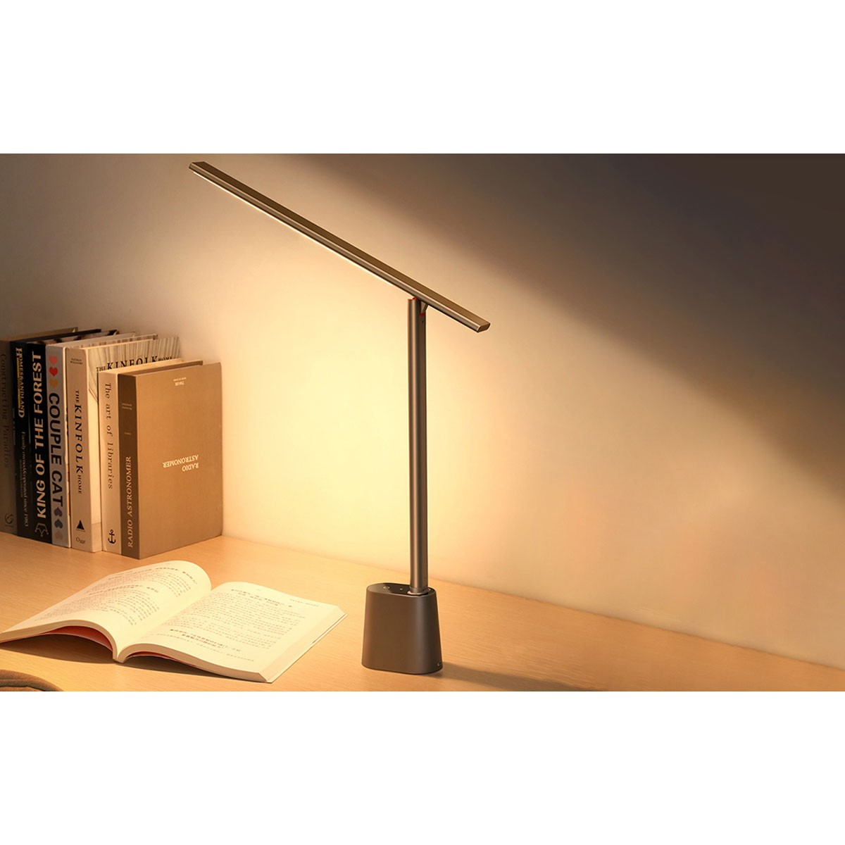 Nowoczesna lampa biurkowa oświetla otwartą książkę i biurko z książkami z boku.