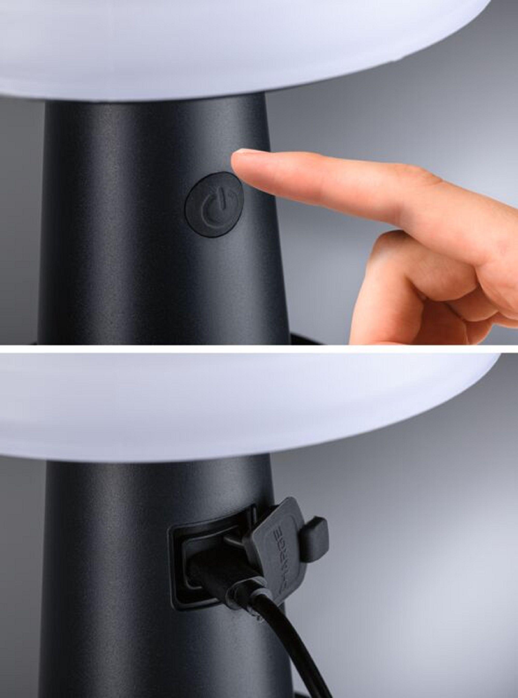 Zbliżenie czarnej lampy. Palec naciska przycisk zasilania.