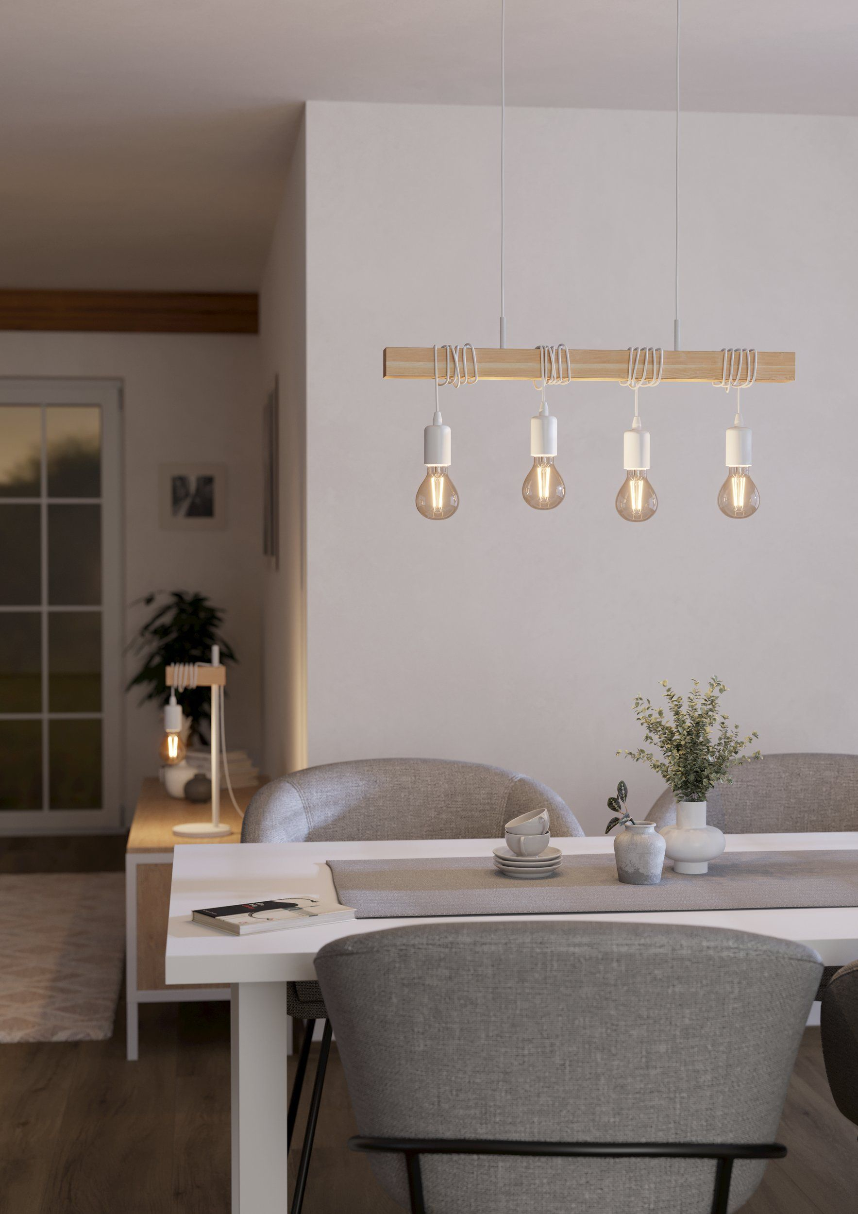 Ein Esszimmer mit weißem Tisch, Stühlen und einem Holzbalken mit hängenden Glühbirnen.
